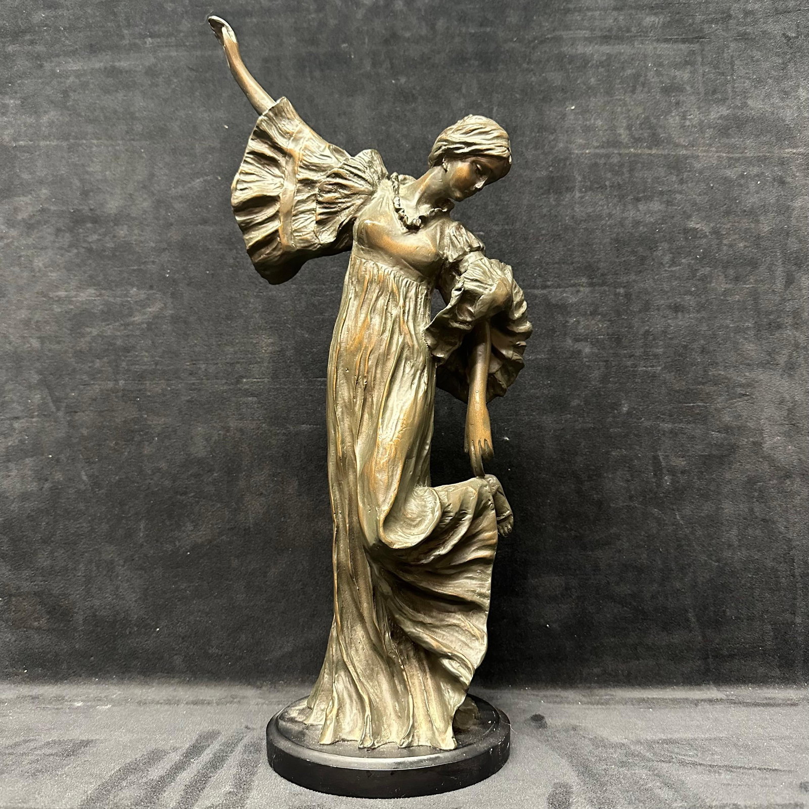 Resin Art Nouveau Style Dancing Woman Art Sculpture on Round Wood Base: A graceful decorative sculpture depicting a flowing-gowned woman in an Art Nouveau–inspired pose. Cast in a composite/resin material with a bronze-tone finish, the figure shows elegant drapery,