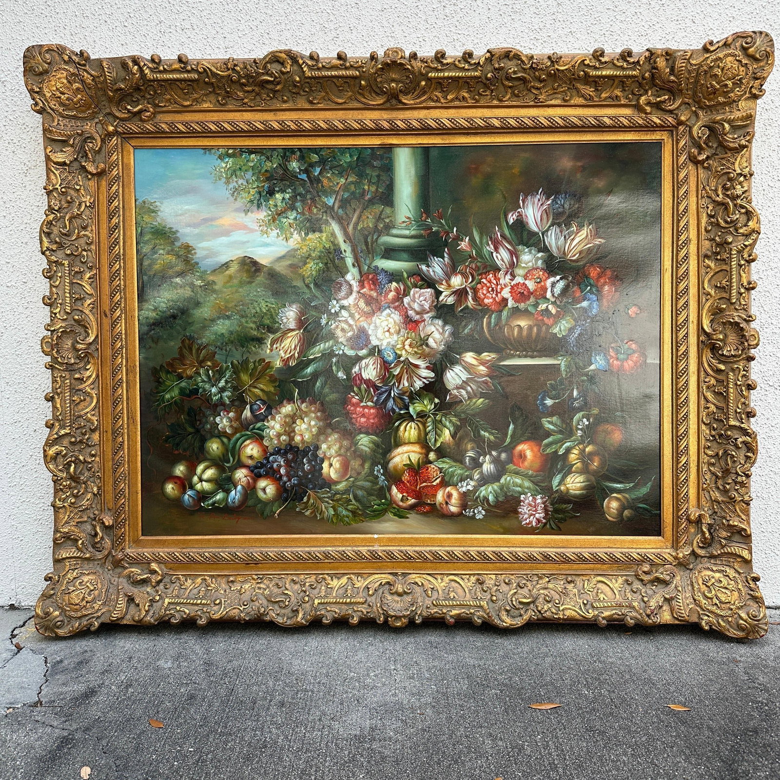 Large Framed Floral And Fruit Still Life Oil Painting After Dutch Masters R235: Large decorative oil painting depicting an elaborate floral and fruit still life with grapes, peaches, pomegranates, tulips, and a landscape background in the Dutch Old Master style. Signed lower left