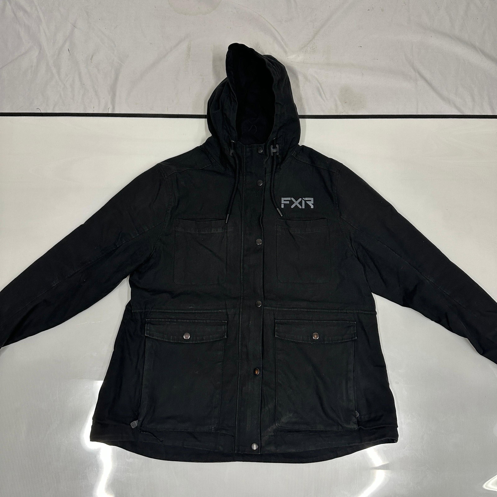 FXR Black Hooded Utility Riding Jacket Coat Size 2XL: FXR black hooded utility style riding jacket marked size 2XL. Features full zip and snap front closure, multiple front flap pockets, adjustable hood drawstrings, and an interior zip pocket. Shell mark