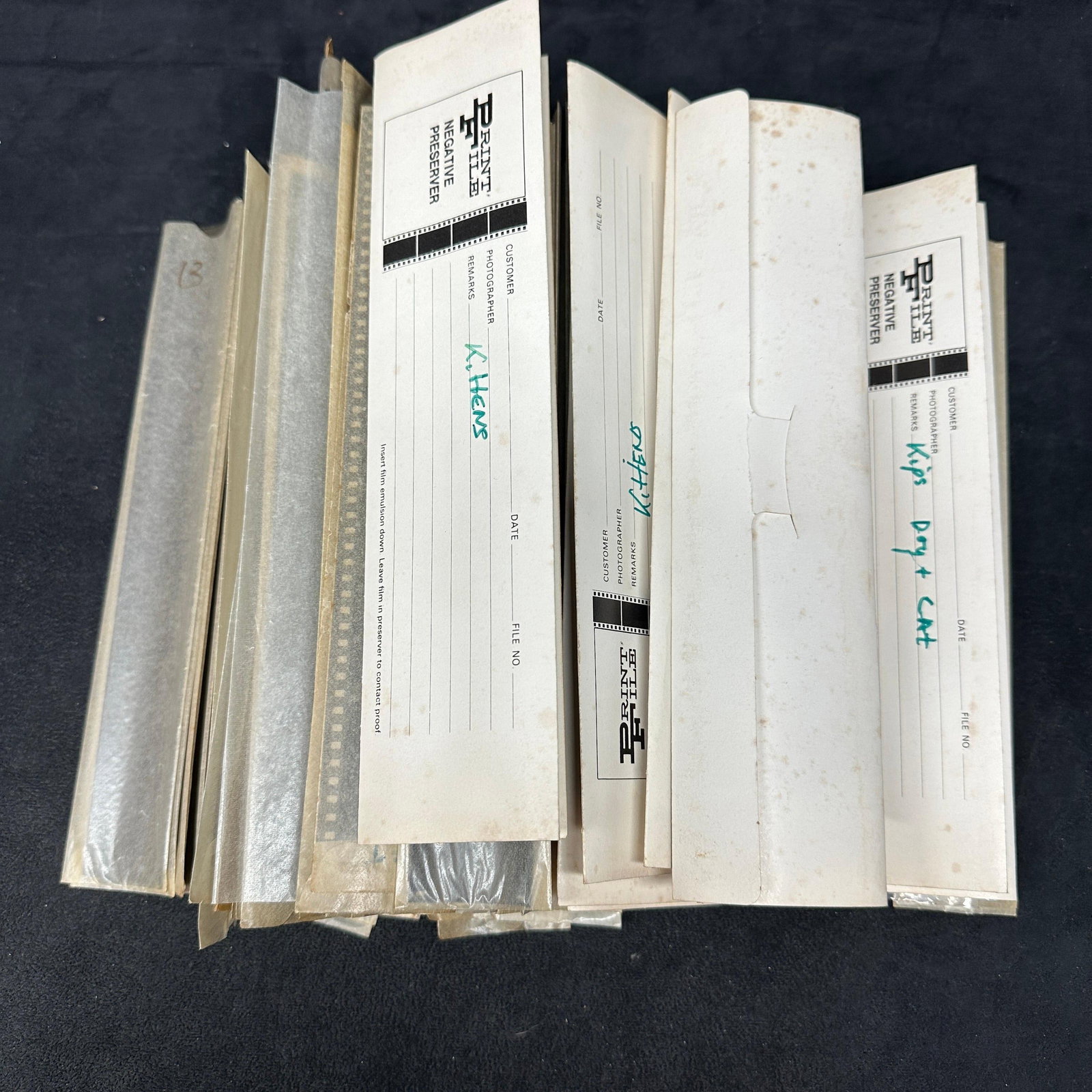 Vintage 35mm Film Negative Archive and Photography Negatives Collection: Large collection of vintage 35mm photographic film negatives, negative sleeves, and archival storage envelopes. Includes numerous developed negative strips depicting buildings, streetscapes, beach