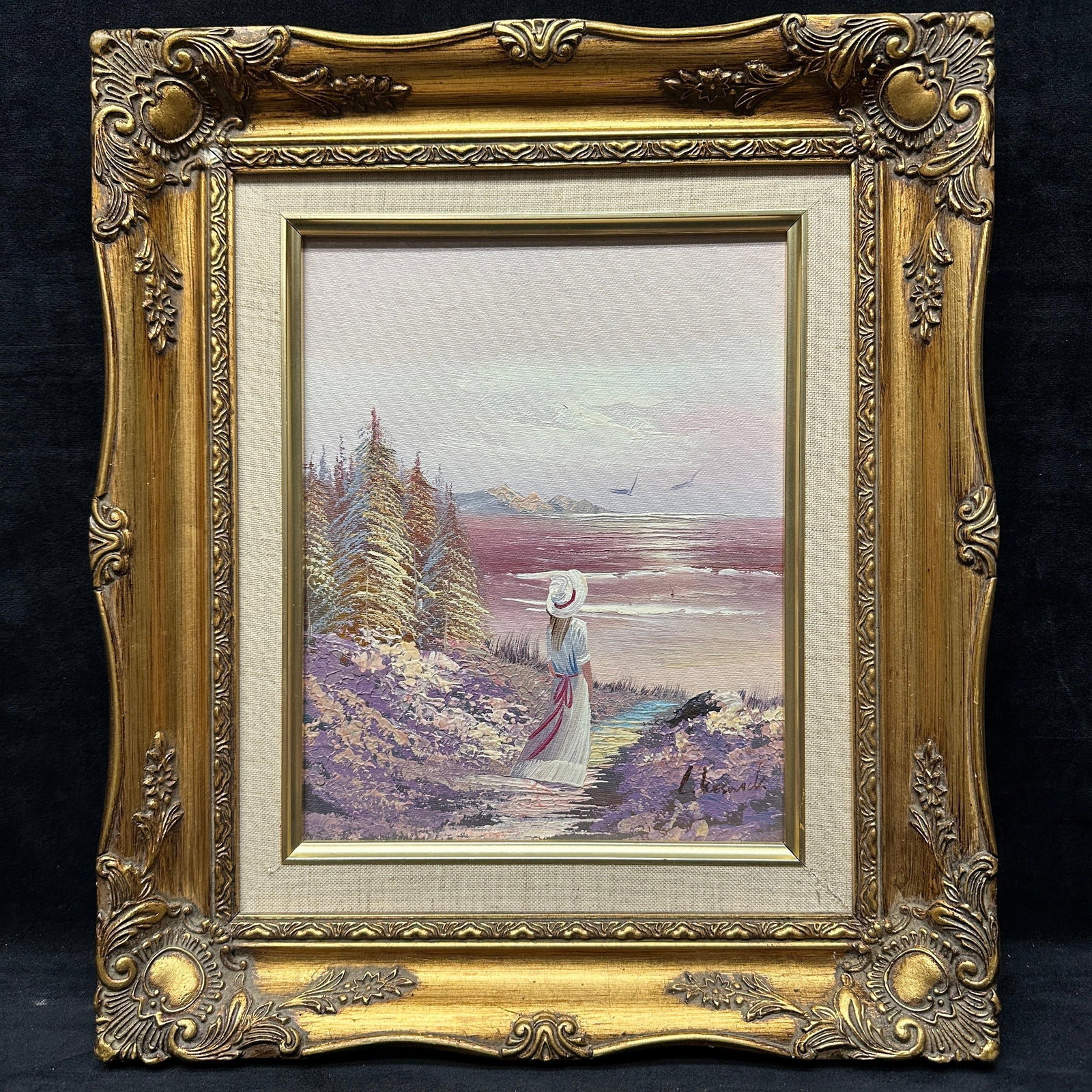 Signed Laura Keswick Impressionist Style Coastal Landscape Oil Painting in Ornate Frame: Framed impressionist style oil painting depicting a woman in a white dress overlooking a coastal shoreline landscape with a floral foreground and evergreen trees. Signed lower right, “L. Keswick