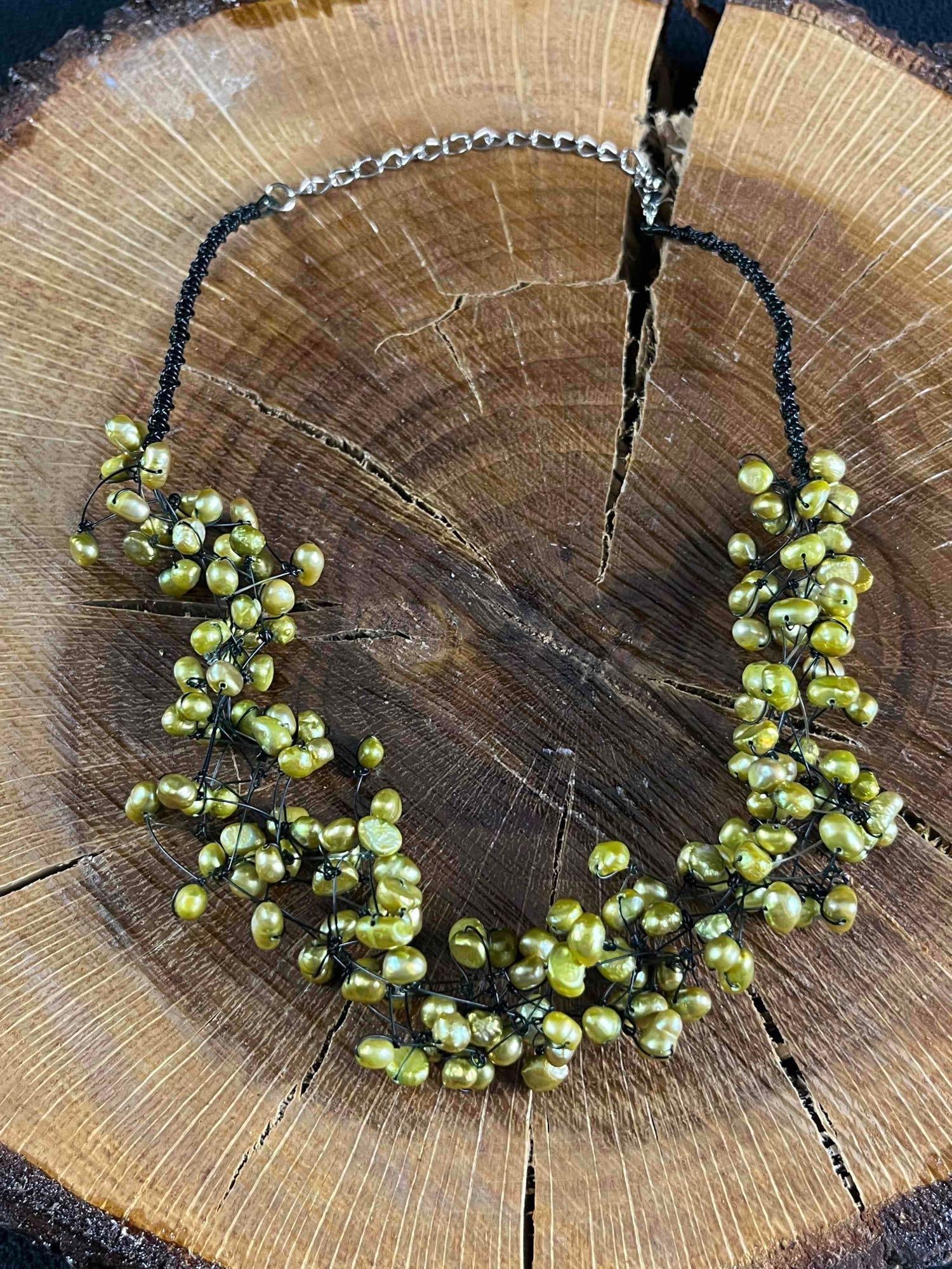 Pearl Necklace Handmade Green Pearl Necklace: Pearl Necklace Handmade Green Pearl Necklace Pictured are cultured green-dyed pearls on a black weaved plastic chain. The pearls are weaved onto the black chain making an organic shape. This necklace