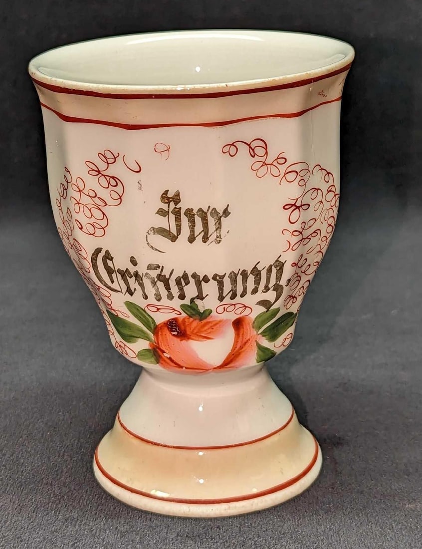Vintage Porcelain German Cup: Vintage Porcelain German Cup. Has a saying on the side we cannot make out. This cup is approx 3 1/2" x 3 1/2" x4 3/4" and it weighs 0.50lb. The cup has some wear on the color and rim. Along with some 