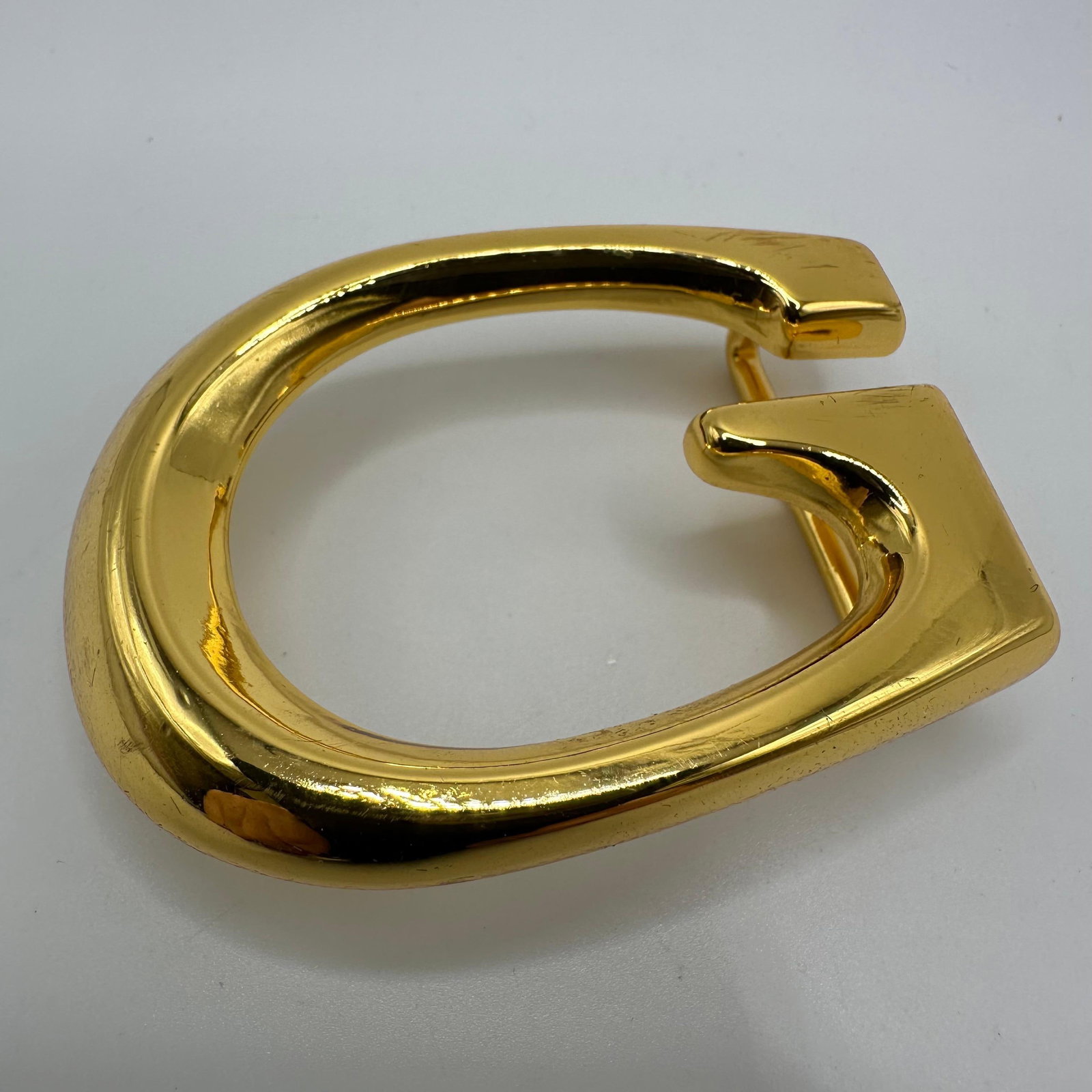 Guuci Italy G Gold Tone Belt Buckle G-Logo: The reverse is marked Gucci Italy. This item is in pre-owned, previously displayed condition with wear and surface scratches. Please reference all photos for full details. Size: 2 1/4" x 1 3/4"