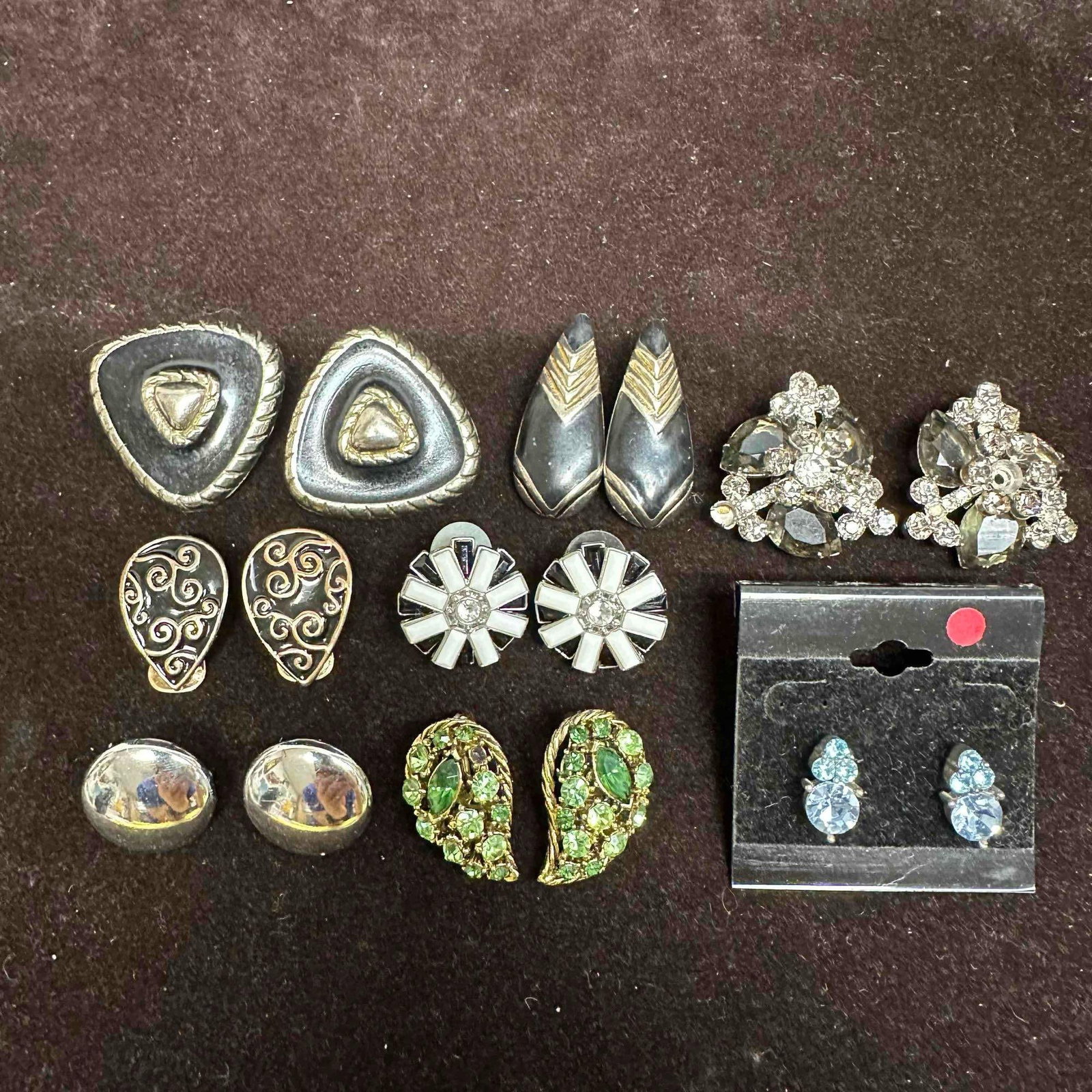 Lot of Costume Earrings Mixed Rhinestone Enamel and Statement Styles K4: Assorted collection of vintage costume jewelry earrings featuring rhinestone floral clusters, geometric enamel clip-ons, silver-tone domes, abstract swirl patterns, and green rhinestone paisley forms.