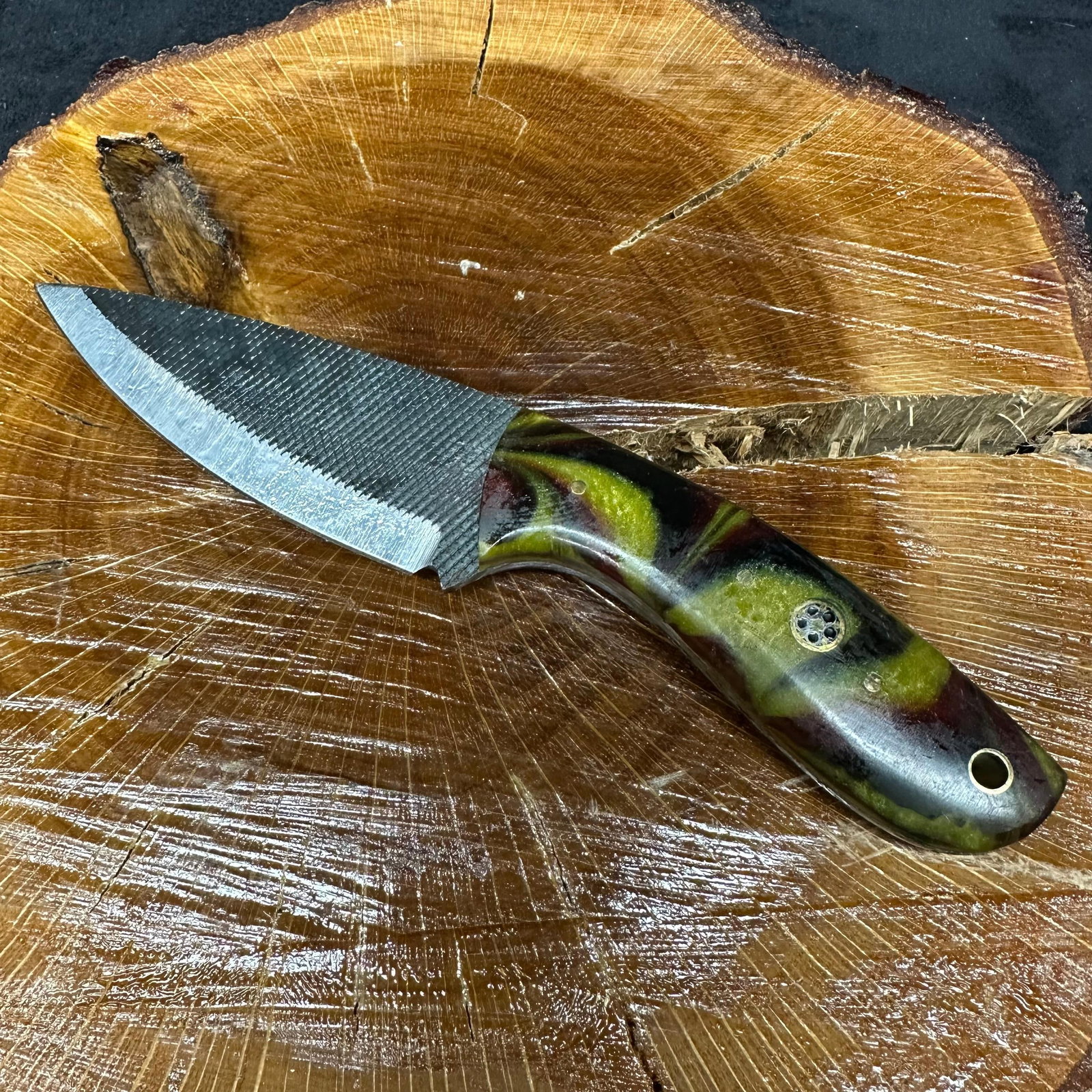 MHS Cutlery Fixed Blade Knife Military Camo Handle with Sheath P46: Fixed blade knife by MHS Cutlery featuring a textured steel blade with a plain cutting edge and decorative spine work. The handle has a contoured, multicolor resin-style grip with metal mosaic pin