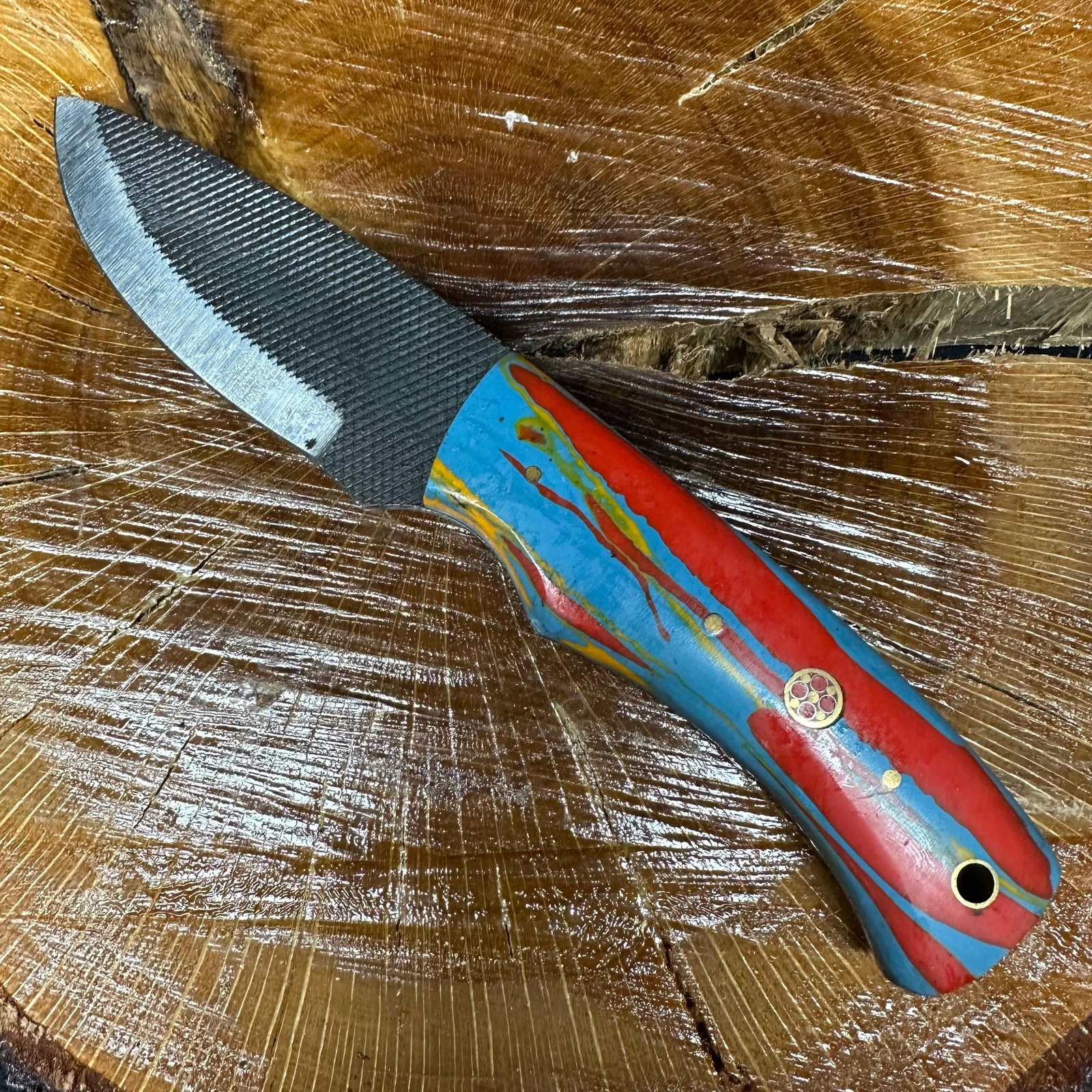 MHS Cutlery Fixed Blade Knife Blue and Red Colored Handle with Sheath P43: Fixed blade knife by MHS Cutlery featuring a textured steel blade with a plain cutting edge and decorative spine work. The handle has a contoured, blue and red resin-style grip with metal mosaic pin