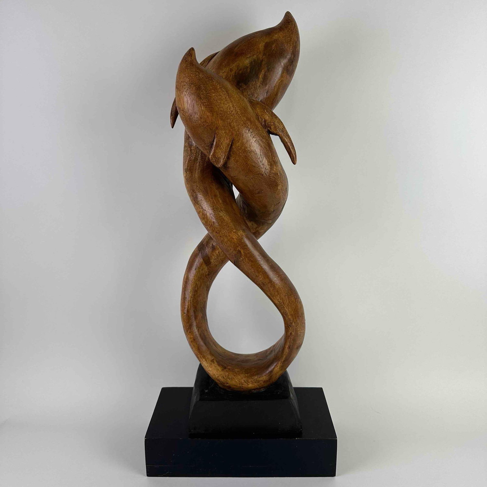 Eternal Dance Dolphin Infinity Shaped Suar Monkeypod Wood Statue Wooden Dolphins Sculpture: The sculpture features two dolphins elegantly intertwined in a fluid, infinity-shaped embrace, capturing a sense of motion and harmony. Hand-carved. The dolphins as well as the middle piece of the bas