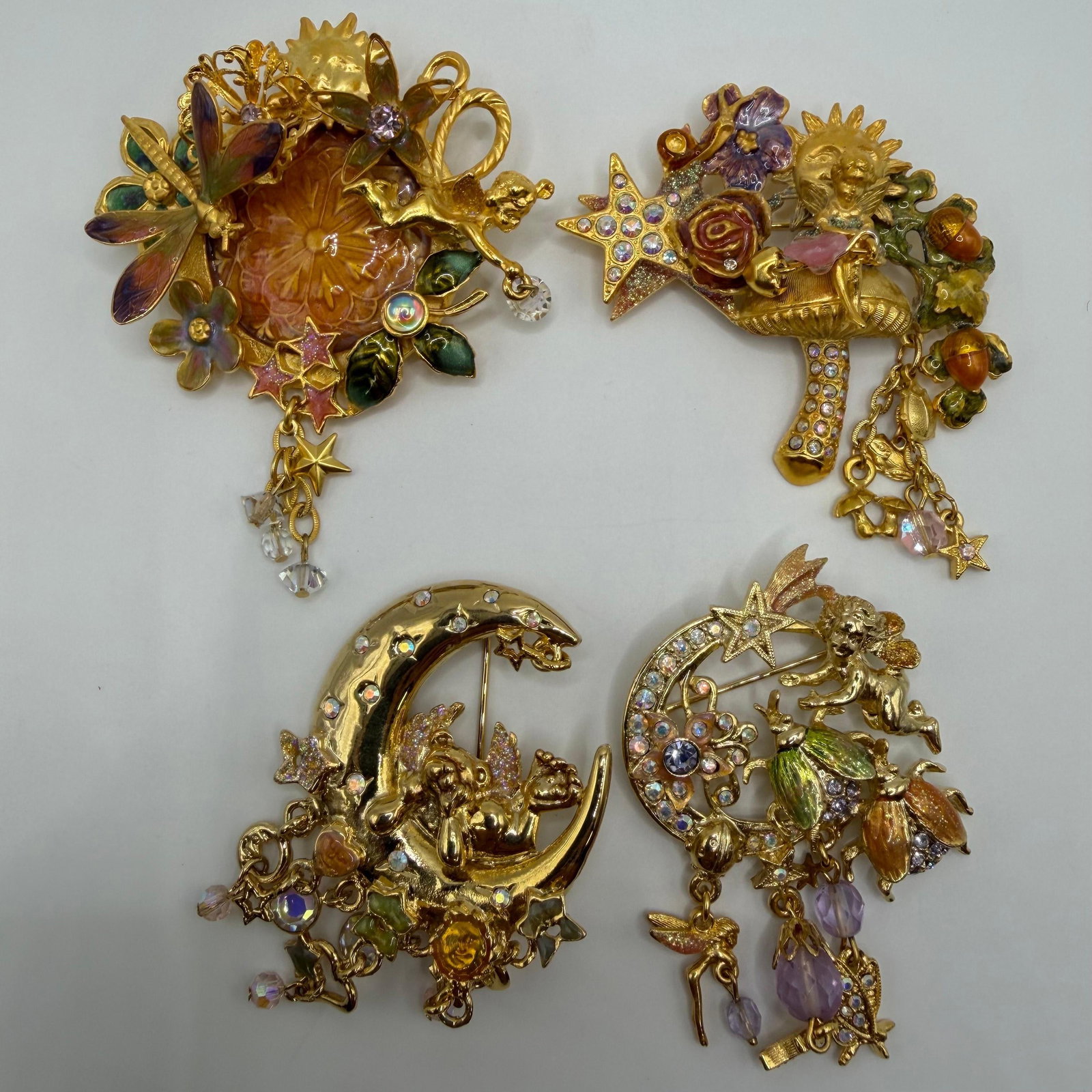 Kirks Folly Gold Tone Fantasy Whimsical Celestial Brooch Set Four Brooches: A lot of four Kirks Folly gold-tone brooches featuring fantasy and celestial themes. Includes fairy, moon, floral, and garden motifs with enamel, rhinestones, and dangling charm accents. All marked Ki