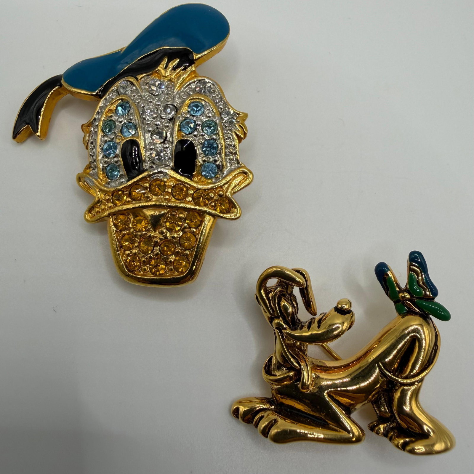 Disney Donald Duck and Pluto Brooch Set Rhinestones Gold Tone: Pluto has a Disney and Napier hallmark; Donald Duck has a Disney and Taiwan hallmark. These items are pre-owned, with light wear, minor imperfections, and surface scratches. Please reference all 