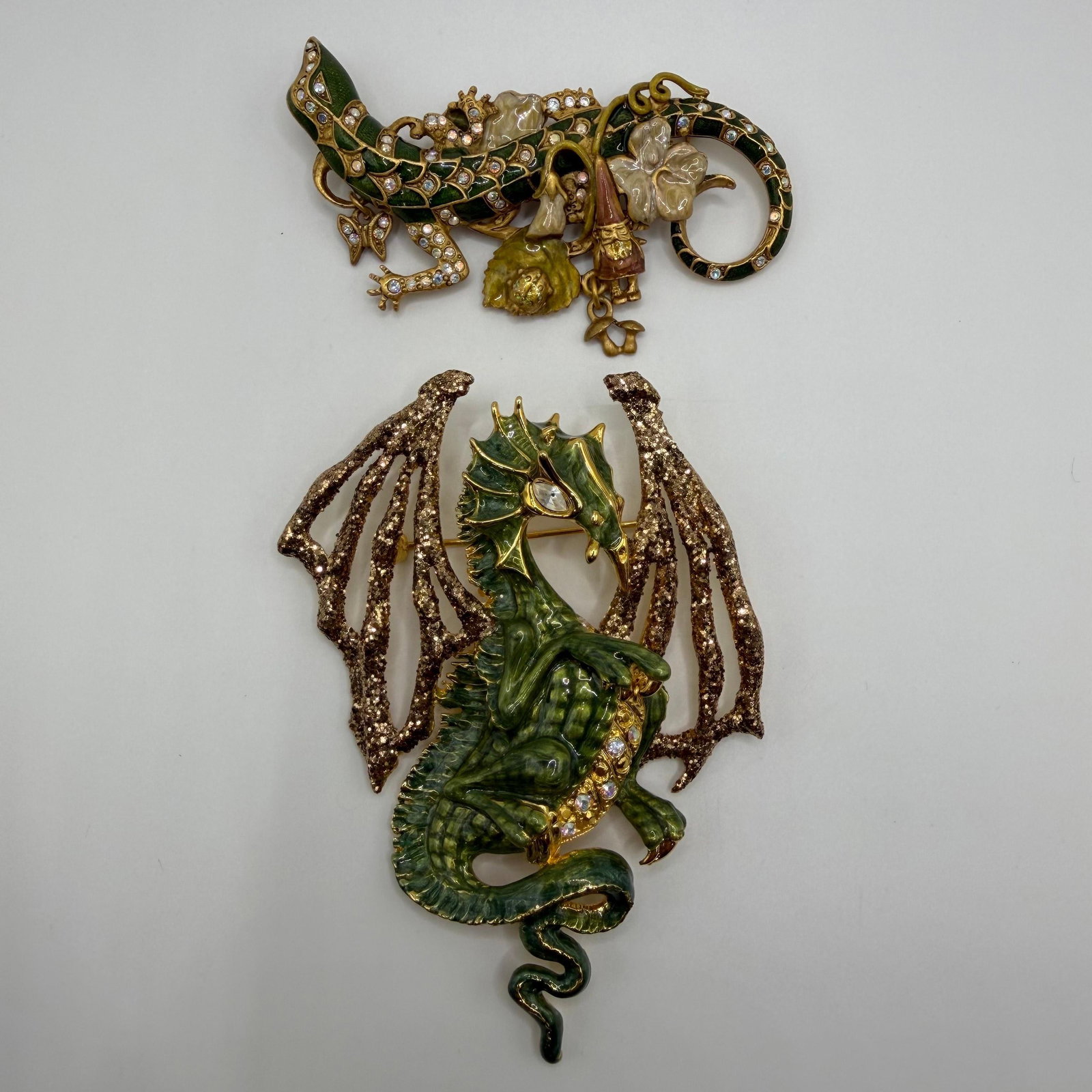 Kirks Folly Draco Dragon and Fantasy Lizard Gnome Designer Brooches 2 Pieces: Pair of Kirks Folly designer brooches featuring fantasy-inspired creatures. Includes a green enamel (Draco 2000) dragon with glittered wings, faux crystal accents, and a faux pearl detail, along with 