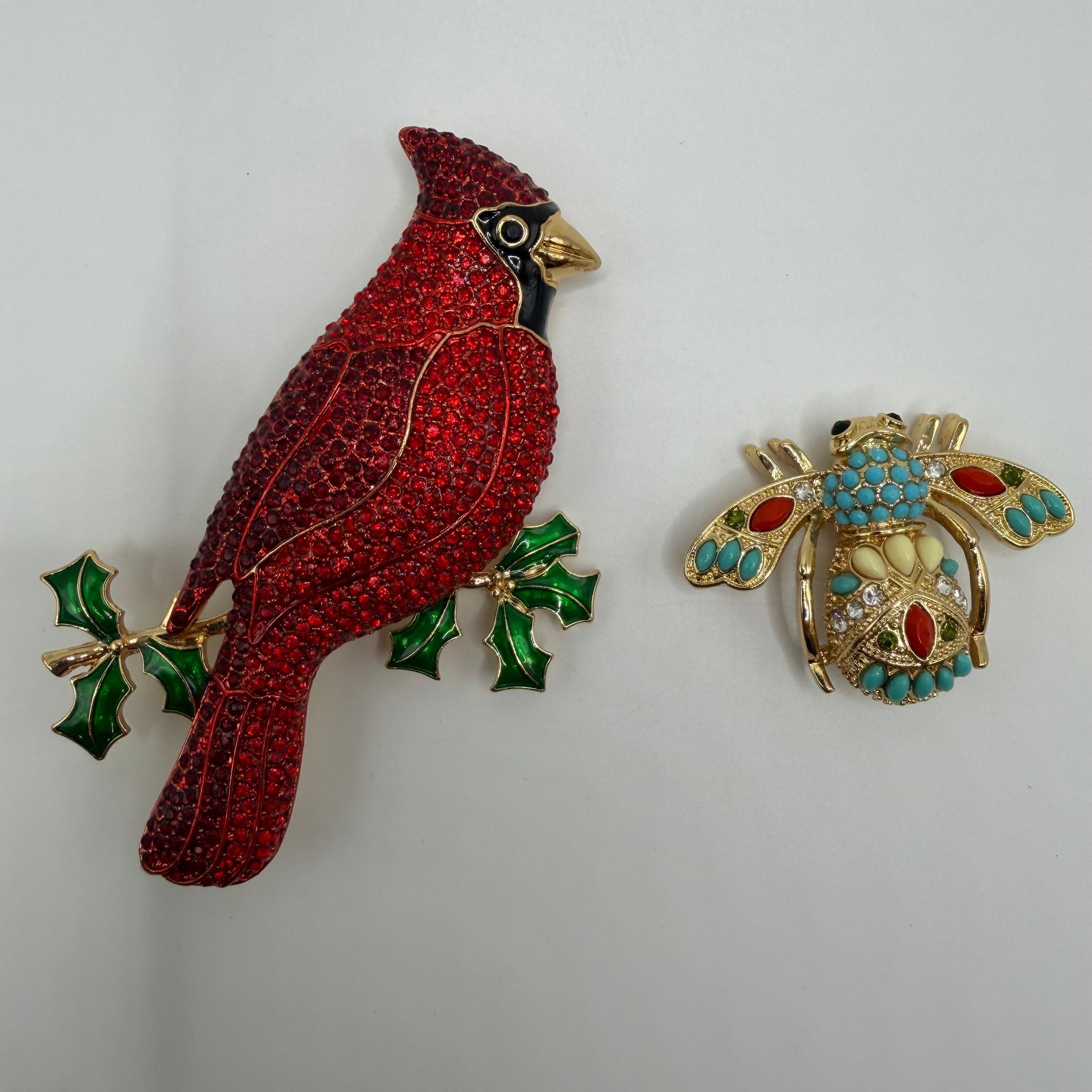 Joan Rivers Classics Collection Crystal Cardinal and Jeweled Bee Brooches: Pair of Joan Rivers Classics Collection gold-tone fashion brooches. Includes a large red crystal cardinal perched on an enameled holly branch and a jeweled bee brooch accented with turquoise-colored c