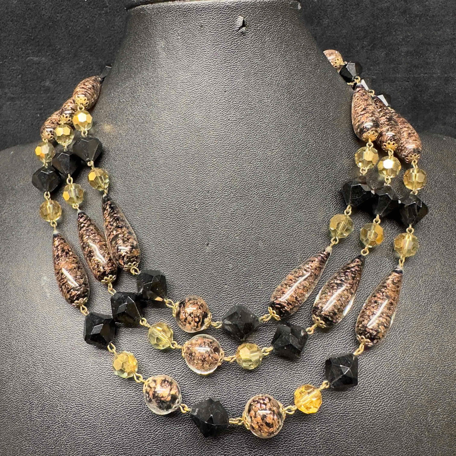 Venetian Murano Lamp Work Art Glass Aventurine Bead Black Beaded Triple Layered Necklace H38: Venetian Murano Lamp Work Art Glass Aventurine Bead Black Beaded Triple Layered Necklace H38. Necklace with black colored glass beads with beautiful designs on each. The necklace features copper accen