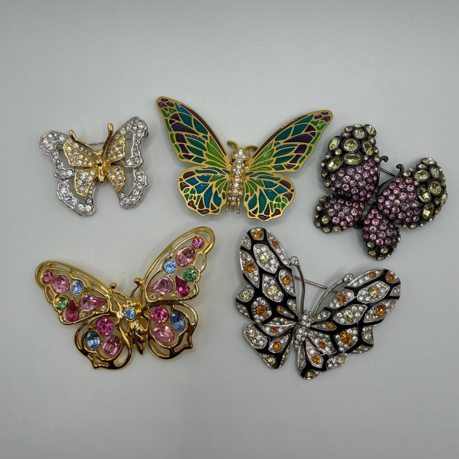 Collection of Five Nolan Miller Butterfly Fashion Brooch Set HG61: Collection of five Nolan Miller butterfly brooches, each marked on the reverse. Includes a variety of colorful designs featuring clear, pink, amber, and green rhinestones, along with hand-painted enam