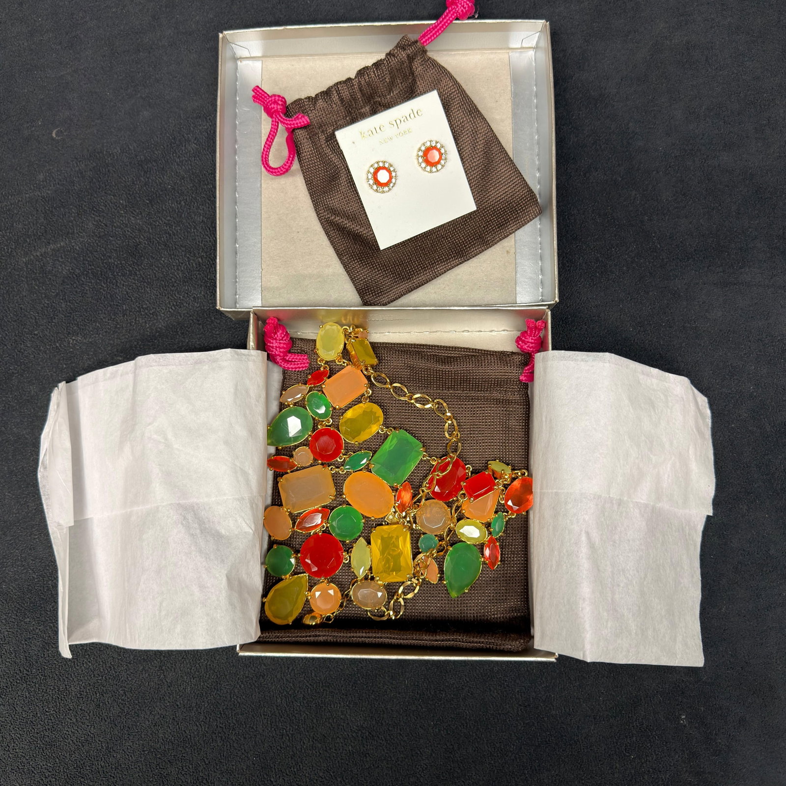 Kate Spade New York Statement Necklace and Stud Earrings Set: Kate Spade New York fashion jewelry set featuring a gold-tone statement necklace adorned with faceted multicolor resin and glass stones in shades of green, orange, yellow, peach, and red. Includes mat