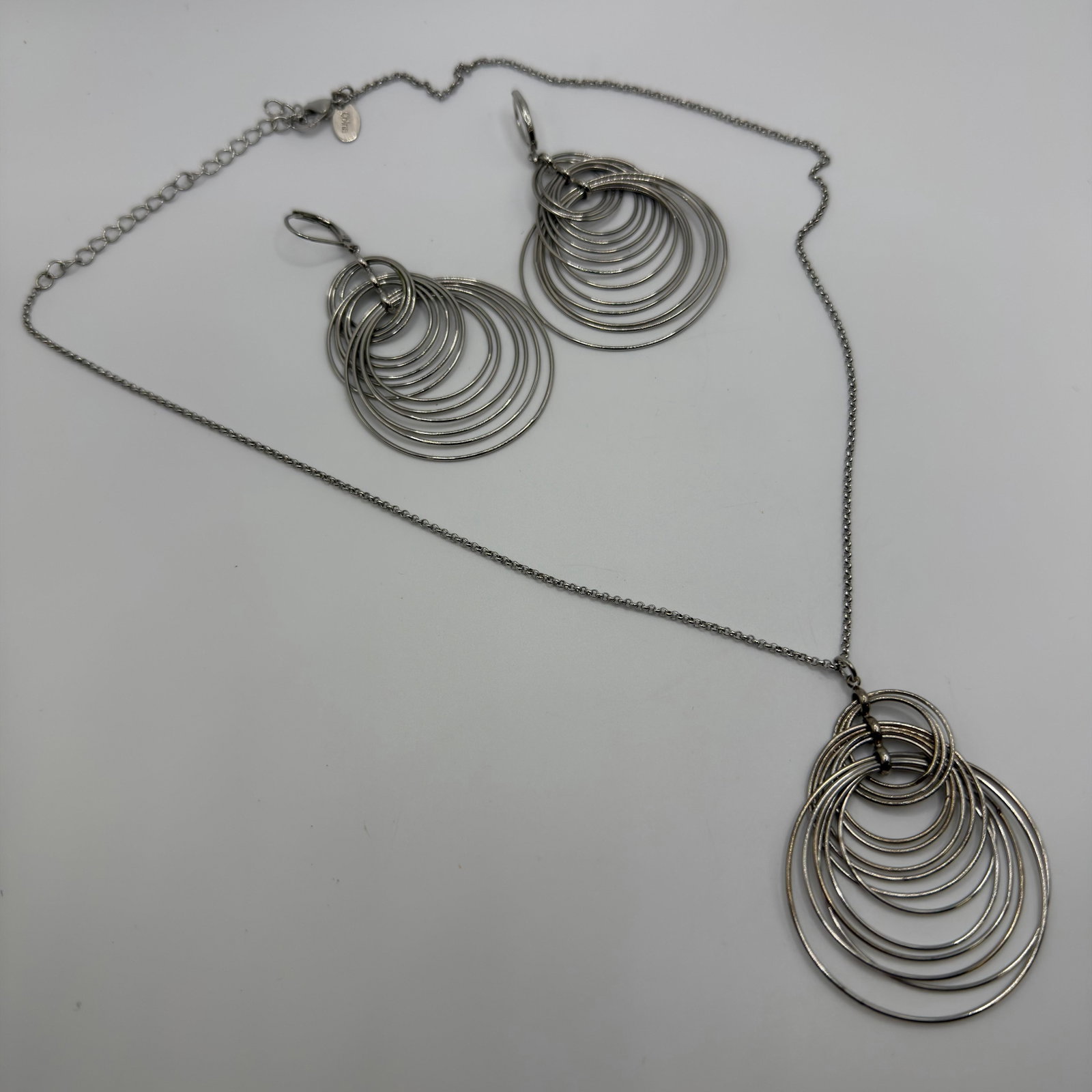 Joan Rivers Modernist Multi-Ring Statement Earrings and Necklace: This is a jewelry set featuring a pair of earrings and a matching necklace marked Joan Rivers. These items are pre-owned, with light wear, minor imperfections, and surface scratches. Please reference 