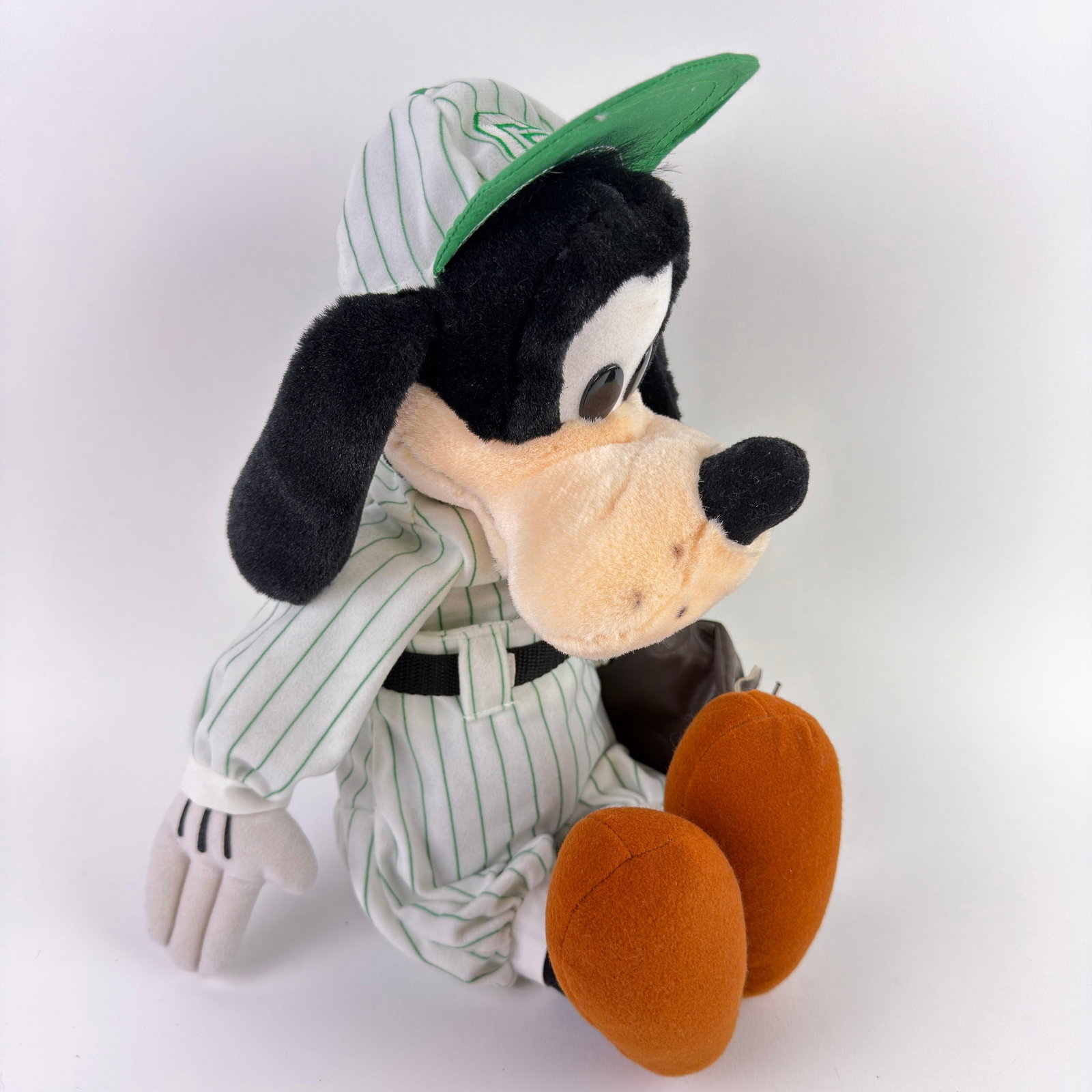 Walt Disney World Goofy Baseball Player Plush with Glove: Walt Disney World Goofy plush, dressed in a white pinstripe baseball uniform with green trim, a matching cap, and a brown baseball glove. Features embroidered and plush details with original Walt Disn