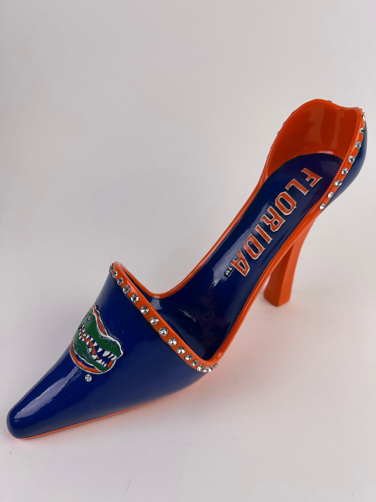 Florida Gator Ceramic High Heel Wine Bottle Holder Rhinestones Orange and Blue: Decorative high-heel shoe wine holder display featuring University of Florida Gators branding. Blue and orange colorway with “Florida” lettering along the insole and Gators logo at the