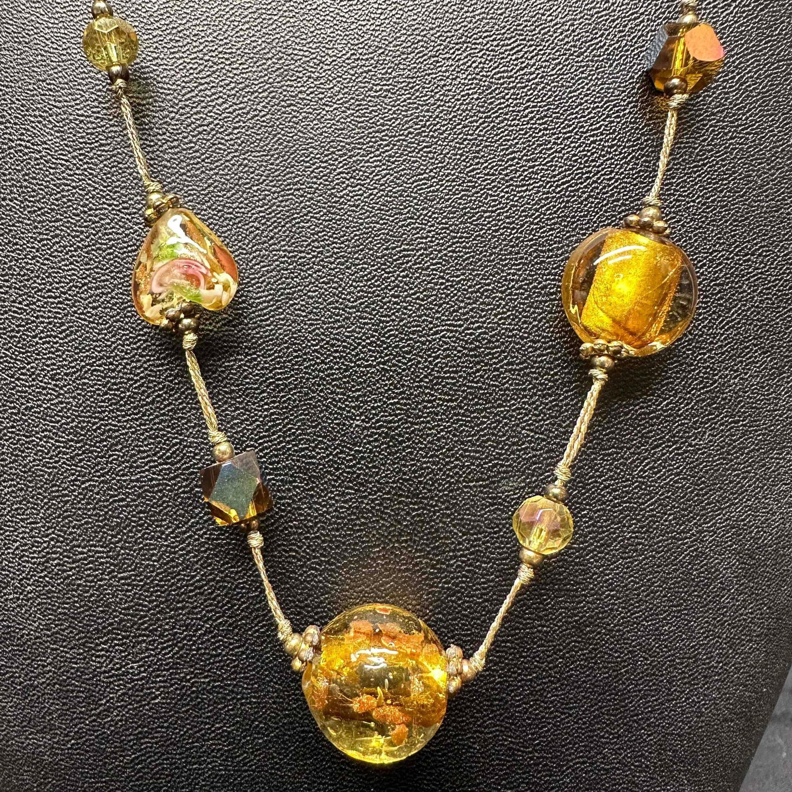 Floral Yellow Gold Venetian Murano Lamp Work Art Glass Necklace: Necklace with yellow and gold colored glass beads with beautiful hand painted designs on each. The necklace features floral, heart shaped, and copper colored accents. The necklace features a lobster