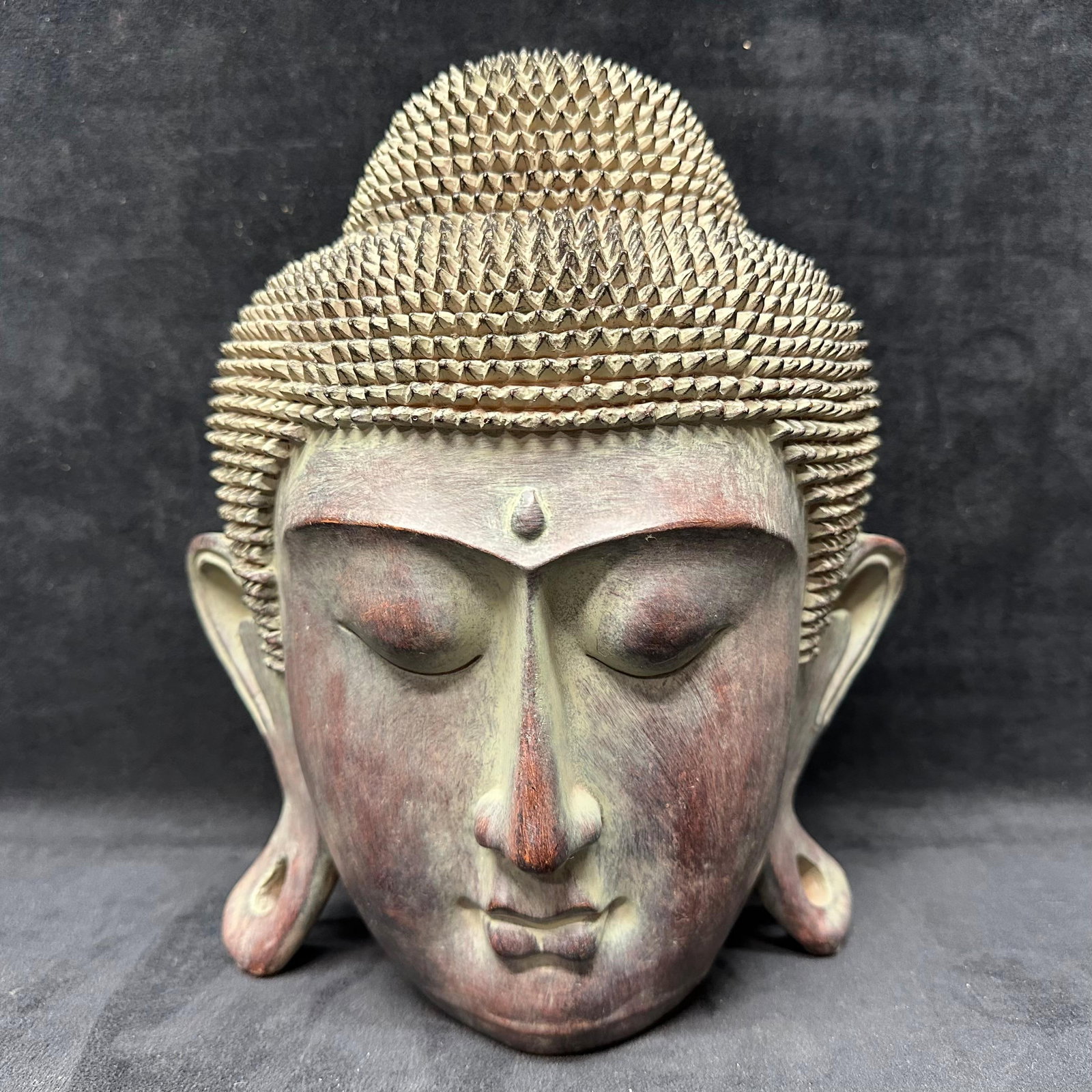 Decorative Buddha Head Modern Asian Style Textured: Decorative Buddha head sculpture featuring a serene expression with closed eyes, elongated earlobes, and finely textured hair. Finished in a mottled gray, bronze, and earthy patina with subtle tonal v