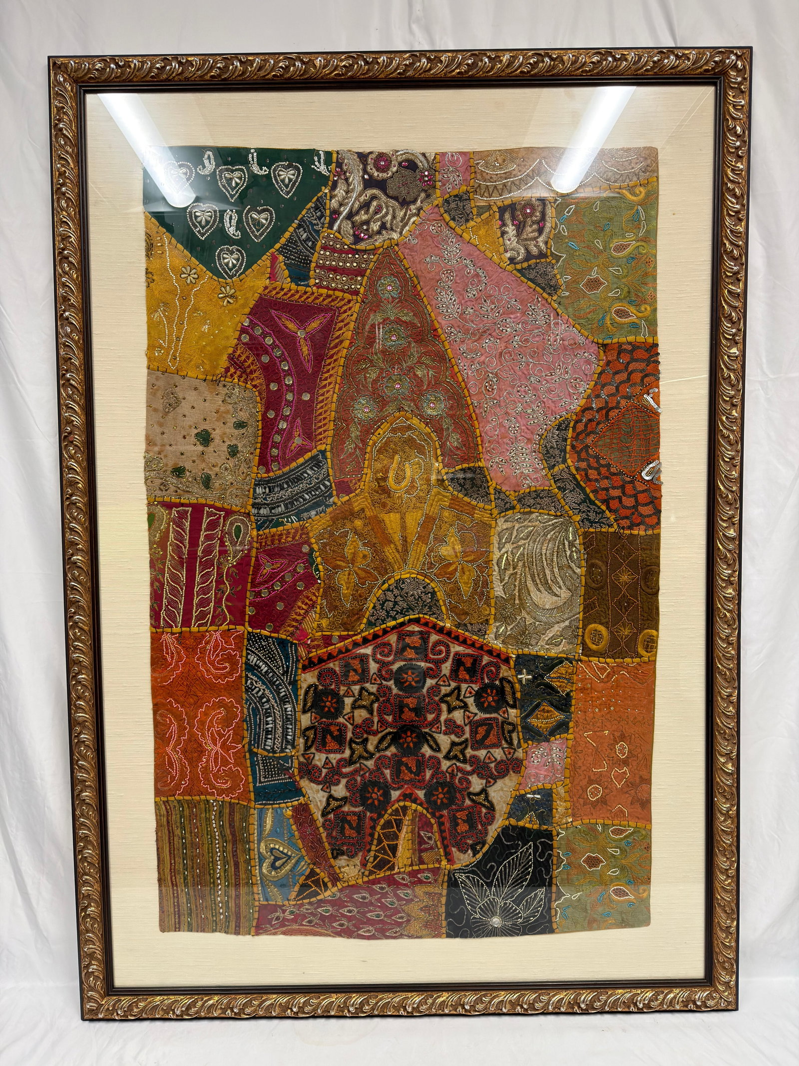 Framed Indian Patchwork Embroidered Colorful Textile Wall Hanging: Decorative framed Indian patchwork textile featuring hand-stitched and embroidered fabric panels with metallic thread, beadwork, sequins, and traditional floral and geometric motifs in warm earth tone