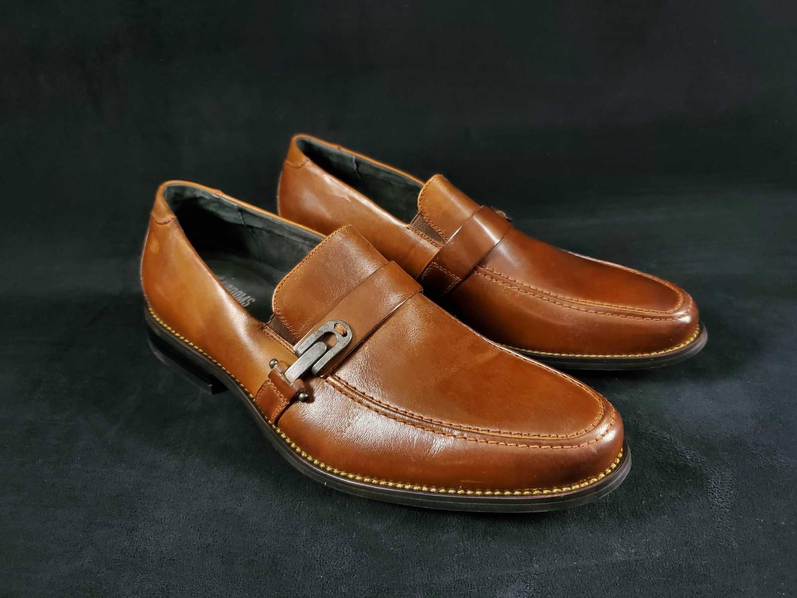 Mens Stacy Adams Fennimore Leather Slip On Size 9: This moc toe slip-on features a decorative strap, a leather upper, leather lining, a fully cushioned insole for added comfort, and a non-leather sole. Comes in original box. Shoes appear to be unused.