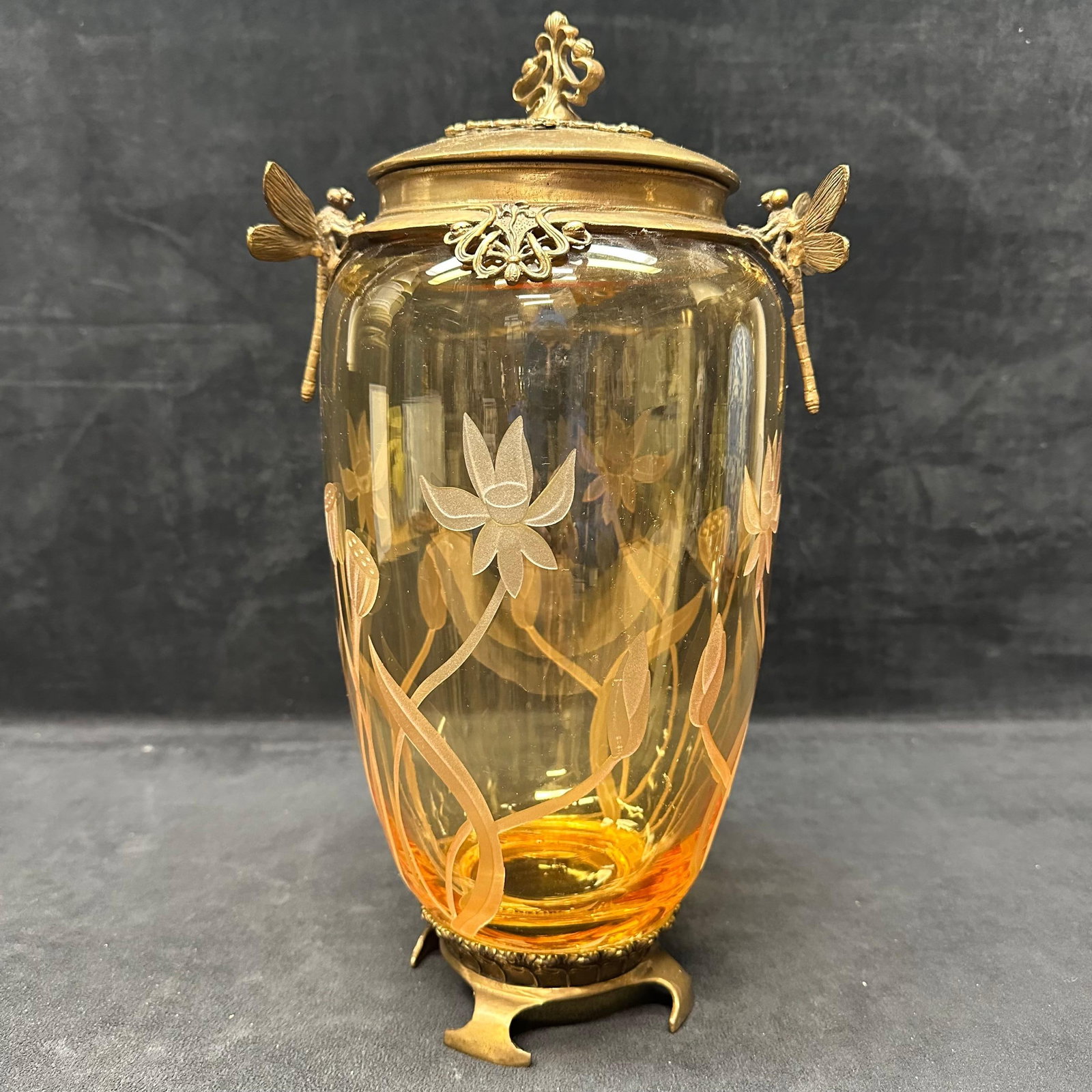 Castilian Art Nouveau Style Amber Glass Lidded Vase with Brass Mounts and Dragonfly Motifs: Decorative Art Nouveau–style vase featuring an amber-toned glass body with acid-etched floral and botanical designs. The glass is mounted in ornate gilt/brass metal with applied dragonfly