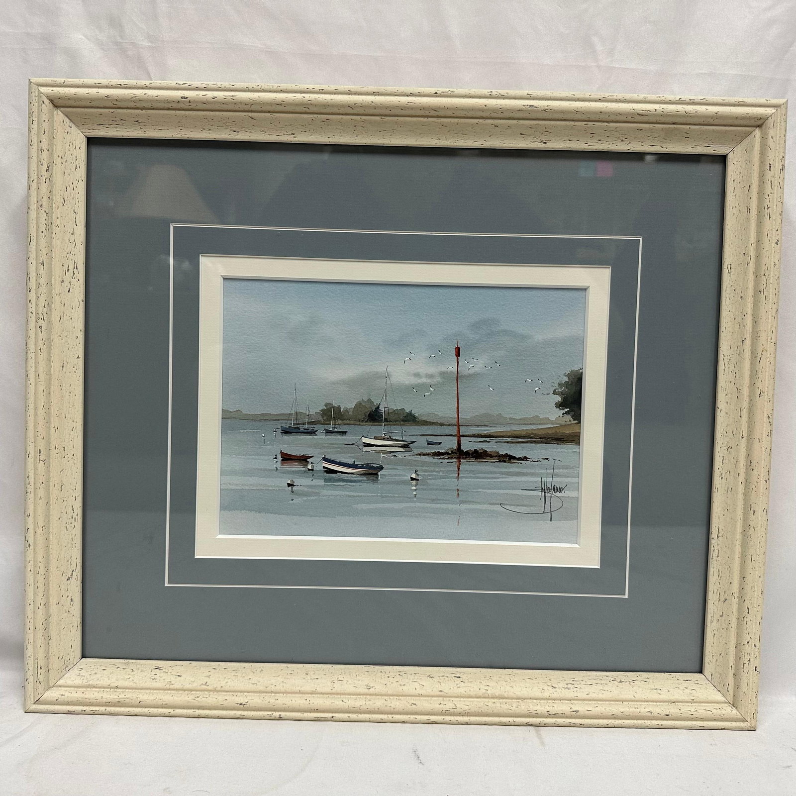 Framed Coastal Harbor Watercolor Painting Boats at Low Tide Artist Signed: Framed coastal harbor watercolor painting depicting small boats at rest in calm waters, with distant shoreline, birds in flight, and a tall red channel marker. Artwork is signed by the artist (signatu