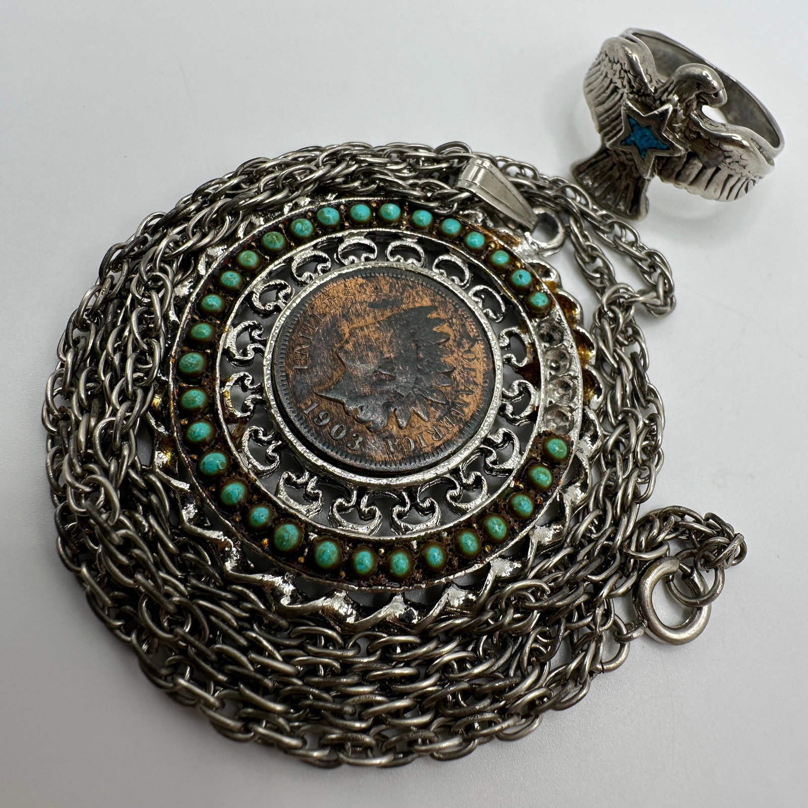 Southwestern Style Indian Head Penny Necklace And Thunderbird Eagle Ring: Southwestern style jewelry grouping including a large pendant necklace centered with a 1903 Indian Head penny surrounded by turquoise-colored cabochon accents and silver tone chain necklace. Also incl