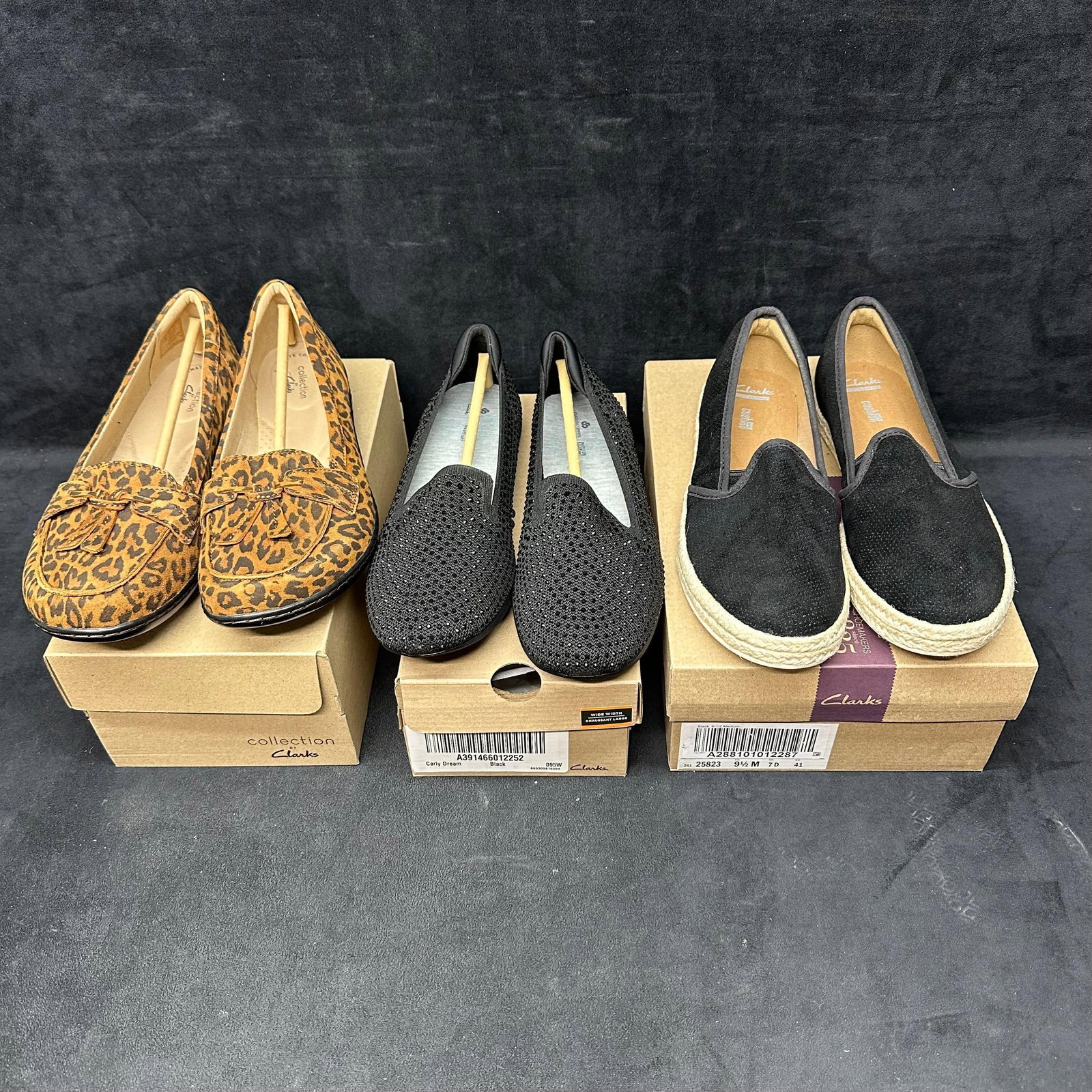 Clarks Women’s Shoes with Boxes Lot of Three Leopard Print Suede: Group of three pairs of Clarks women’s shoes, all appearing new in boxes. Includes one pair of leopard-print suede loafers with bow detail, one pair of black knit slip-ons with subtle rhinestone