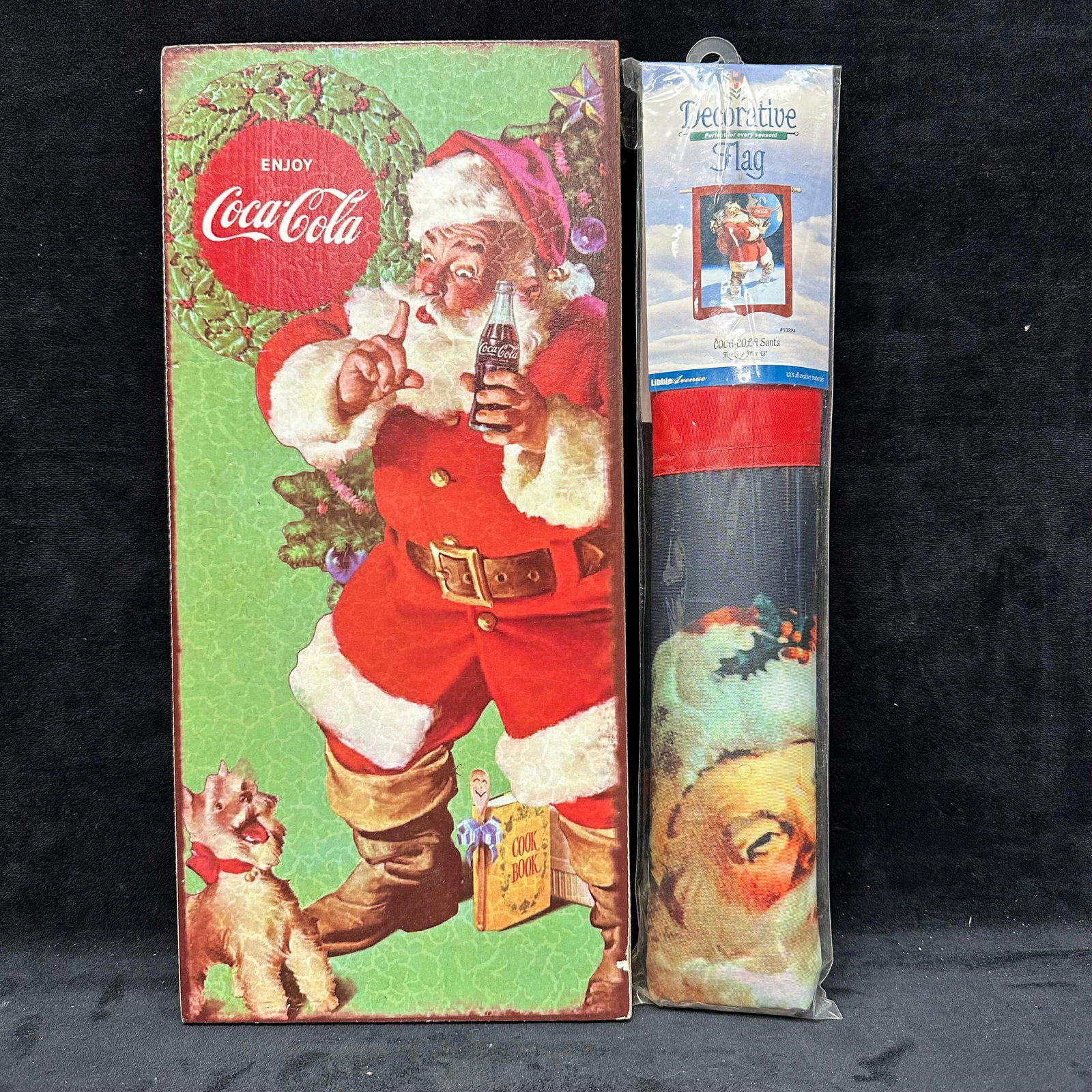 Coca Cola Coke Decorative Flag and Wooden Wall Sign: Two Coca-Cola memorabilia collectibles, including a 29" x 43" flag and a Enjoy Coke Santa wooden sign. These items are in good pre-owned, previously displayed condition with light wear an