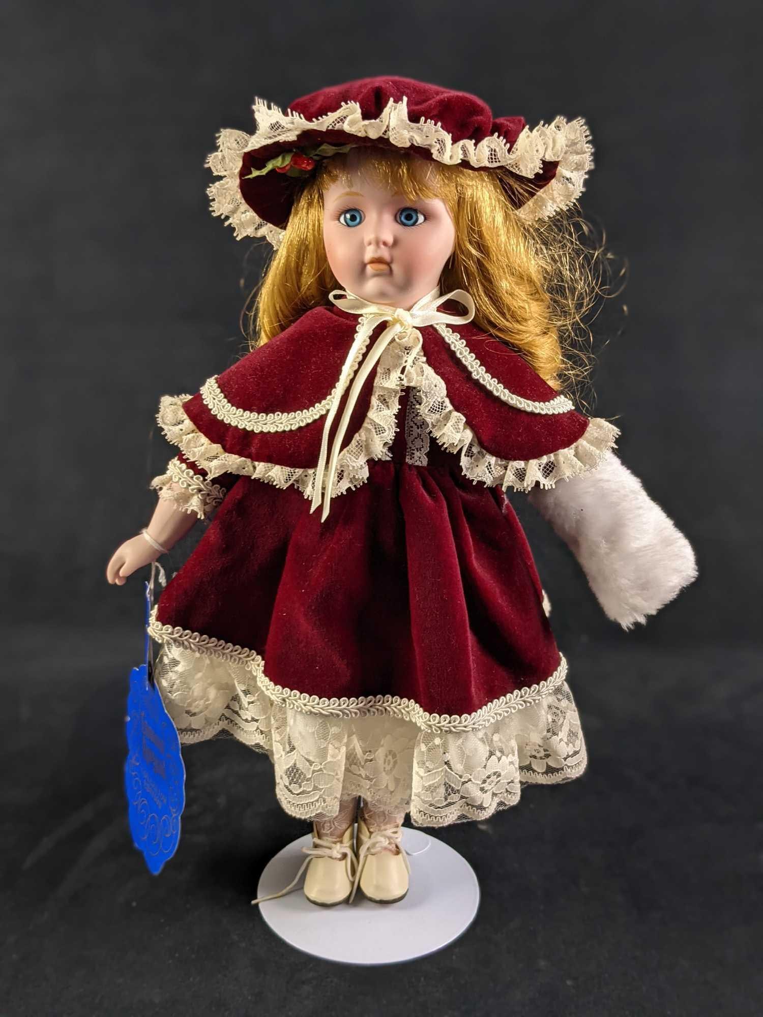 Crown Royal Collector Edition Victoria Noel Porcelain Doll: This porcelain doll is wearing a burgundy velvet dress with a cream-colored trim, and a matching hat. She also has a white muff to keep her hands warm. Doll comes with its own stand. The doll is appro