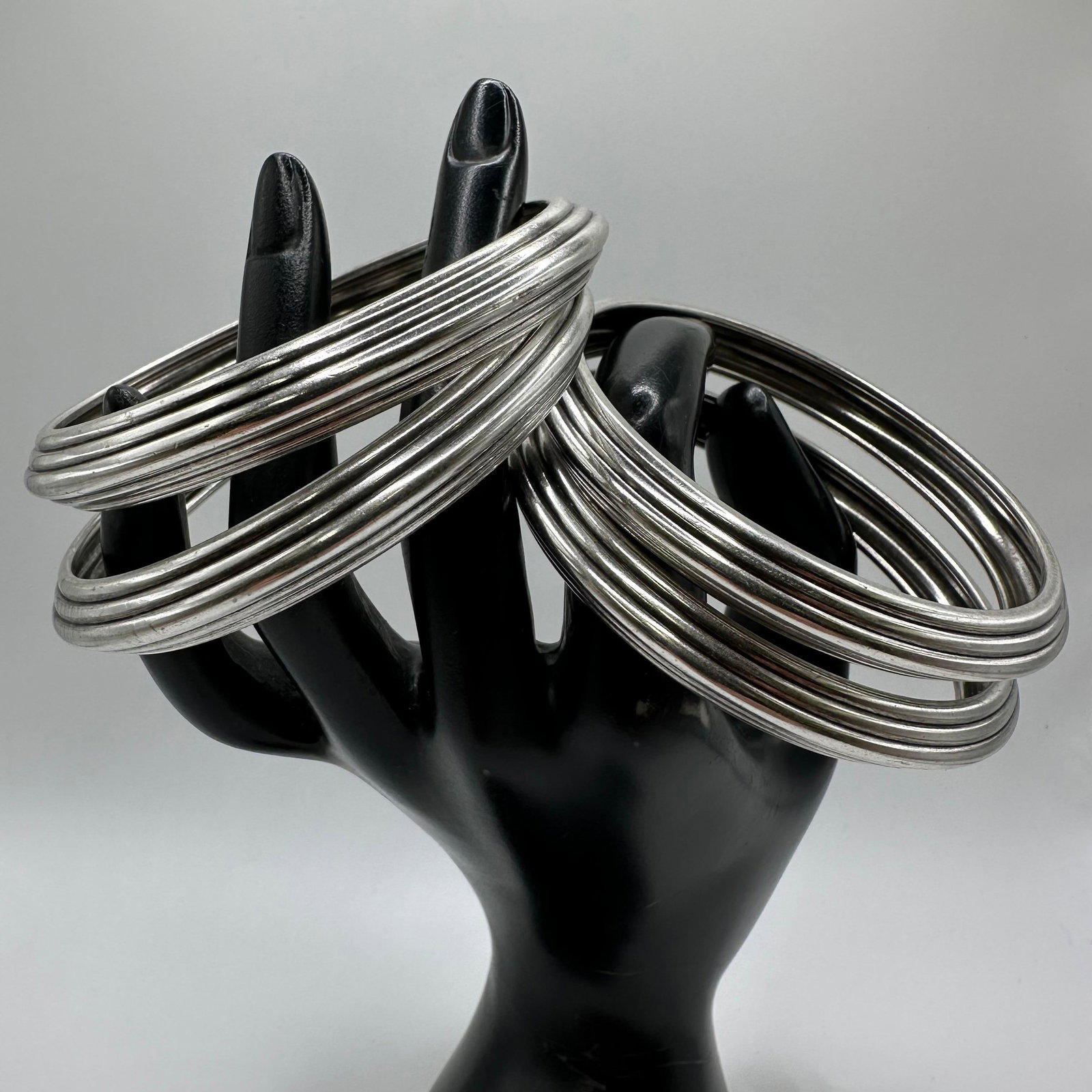 Group Of Silver Plated Bangle Bracelets Ribbed Stackable Jewelry Lot Four: A lot of silver-plated bangle bracelets featuring a ribbed multi-band design. Includes multiple matching bangles suitable for stacking or individual wear. Unmarked, silver-plated. Light surface wear a