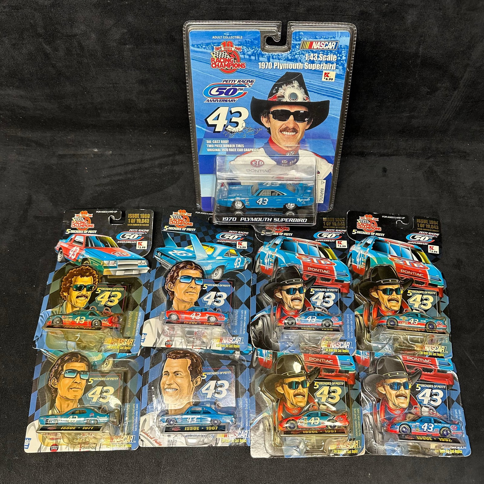 Richard Petty #43 NASCAR Die-Cast Collection Racing Champions Decades of Petty 1:43 Scale: Group of Richard Petty #43 NASCAR die-cast cars by Racing Champions, including the Petty Racing 50th Anniversary and 5 Decades of Petty series. The lot features multiple carded 1:43 scale die-cast rep