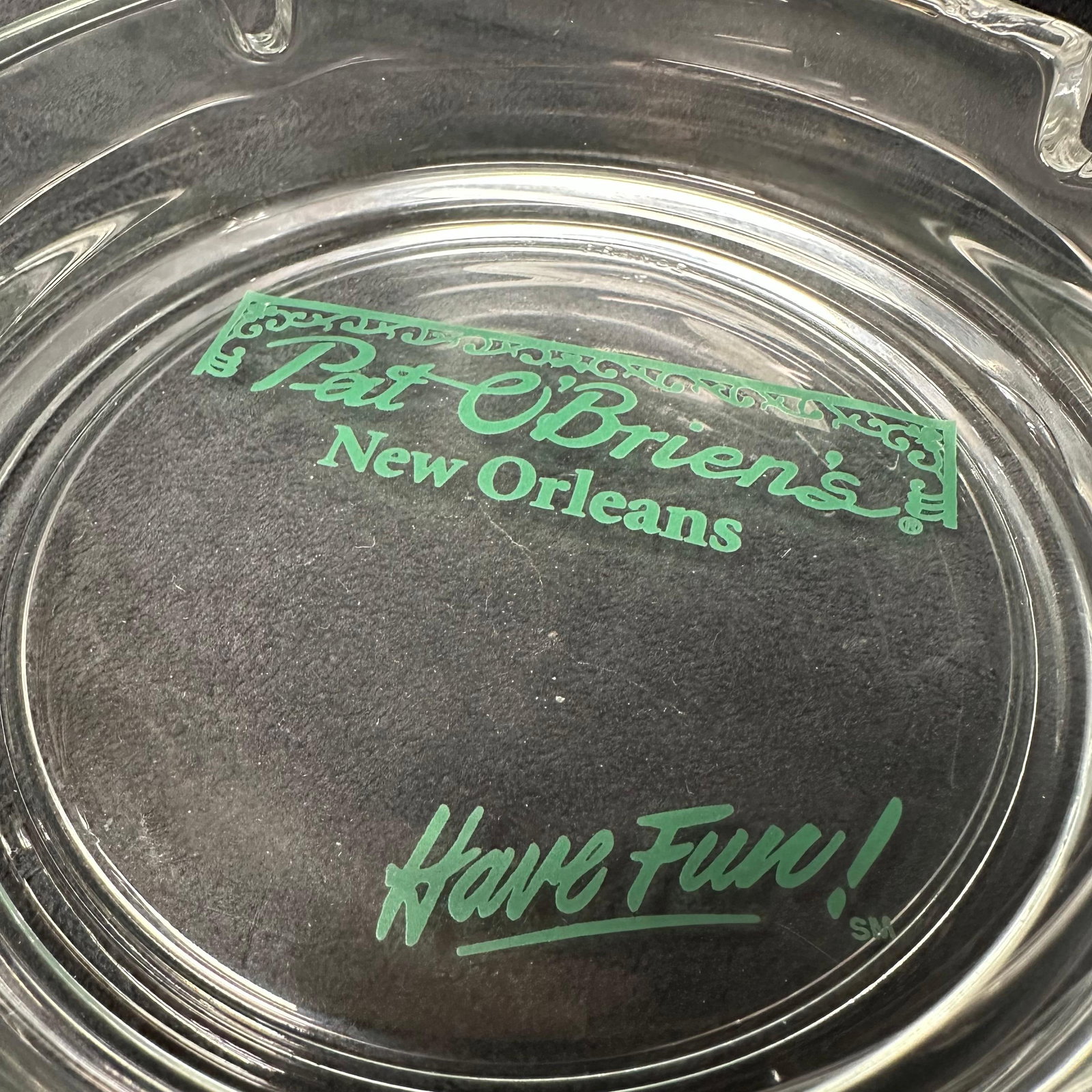Pat O’Brien’s New Orleans Glass Ashtray Have Fun France: Clear glass Pat O’Brien’s New Orleans souvenir ashtray featuring the bar’s iconic green logo and “Have Fun!” slogan. Marked France on the rim. Minor production error on t