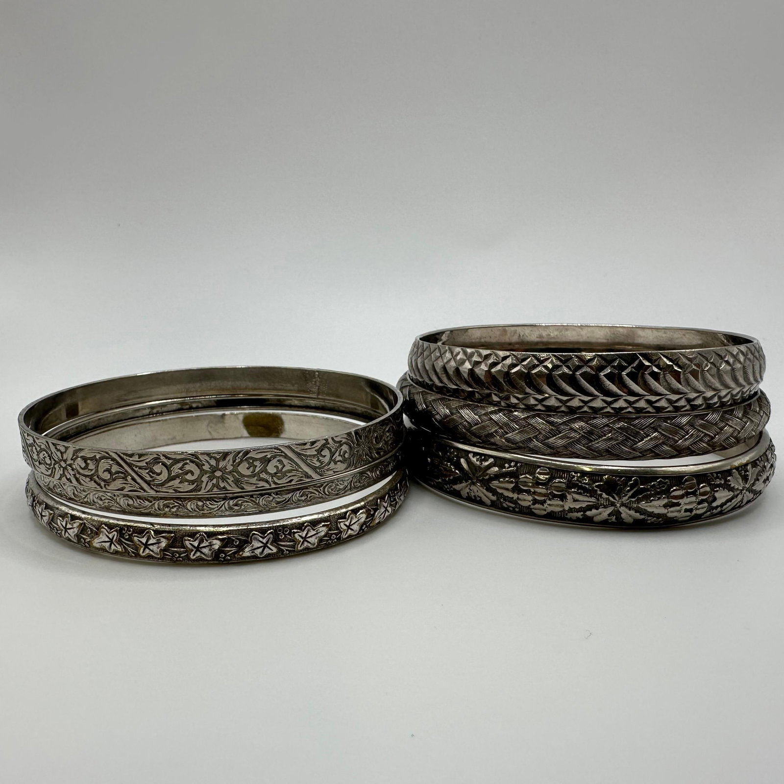 Vintage Etched and Textured Bangle Bracelet Lot Mixed Metal Silver Tone Unmarked: A lot of vintage bangle bracelets feature detailed etched, engraved, and textured designs, including floral, star, braided, and geometric patterns. All pieces are unmarked with no visible hallmarks. A