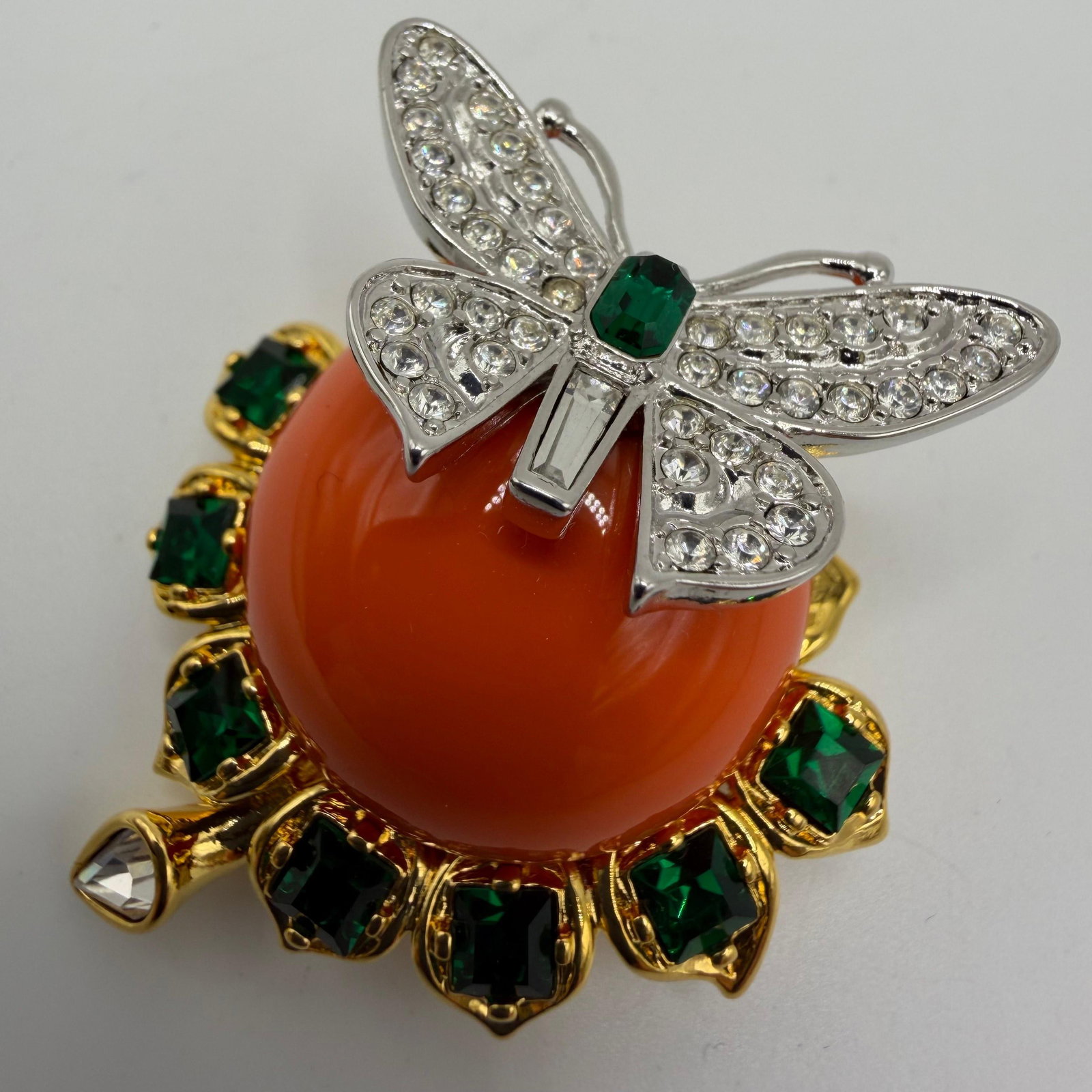Kenneth Jay Lane Treasures of the Duchess Jeweled Butterfly KJL Brooch: Kenneth Jay Lane Treasures of the Duchess collection figural butterfly and floral brooch featuring a domed orange faux coral cabochon-style center accented by faceted green rhinestones, a clear pear-s