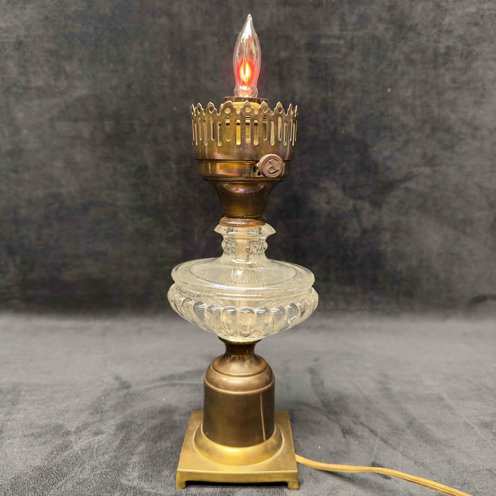 Brass Glass Table Lamp Flame Flicker Bulb: Brass Glass Table Lamp Flame Flicker Bulb. The brass base features a round smooth design. The middle of the lamp has a gorgeous glass design. The lamp has an older power cord with generous length of c