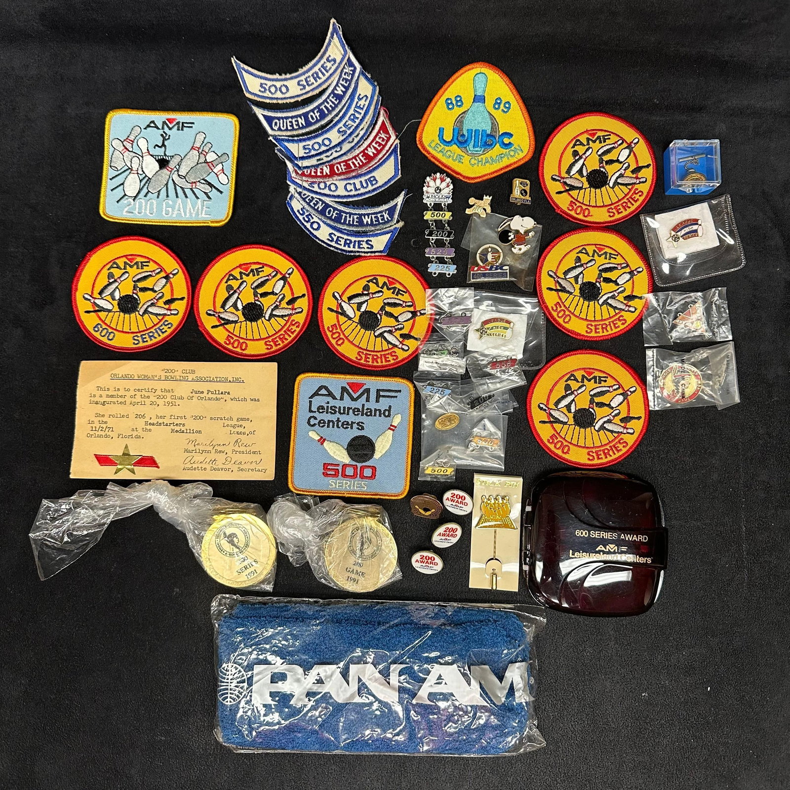 AMF Bowling Awards Collection with Patches Pins and Memorabilia Series Pan Am Armband: Extensive vintage AMF bowling award collection featuring assorted embroidered patches, enamel pins, medals, and key chains representing 200, 500, and 600 series achievements. Includes AMF Leisureland 