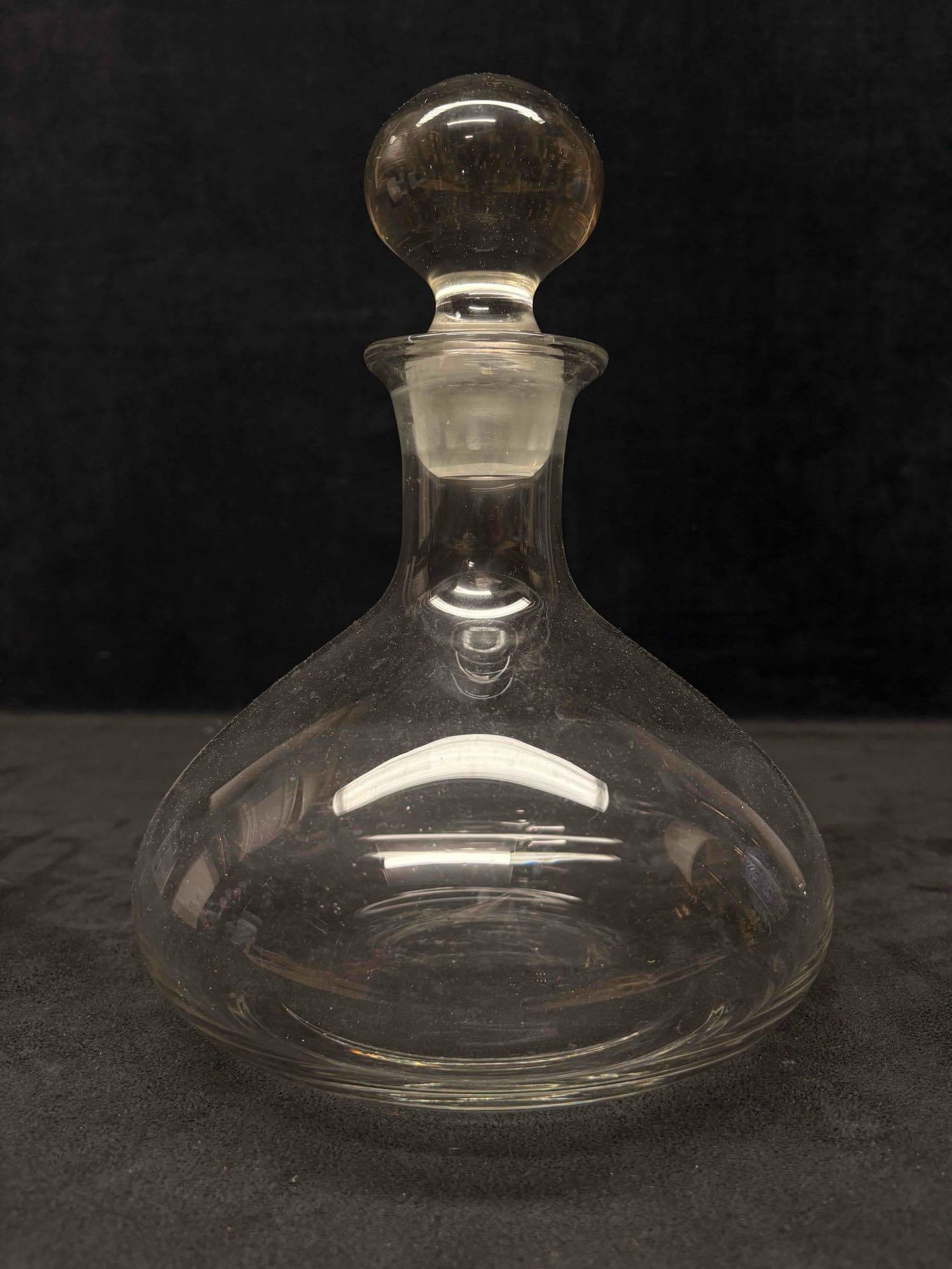 Clear Glass Ships Decanter with Ball-Shaped Topper: This lot contains a vintage glass decanter. The body of the decanter being on the wider side, with a long neck and bulbous stopper. This style commonly referred to as "Ship's Decanter". Ma