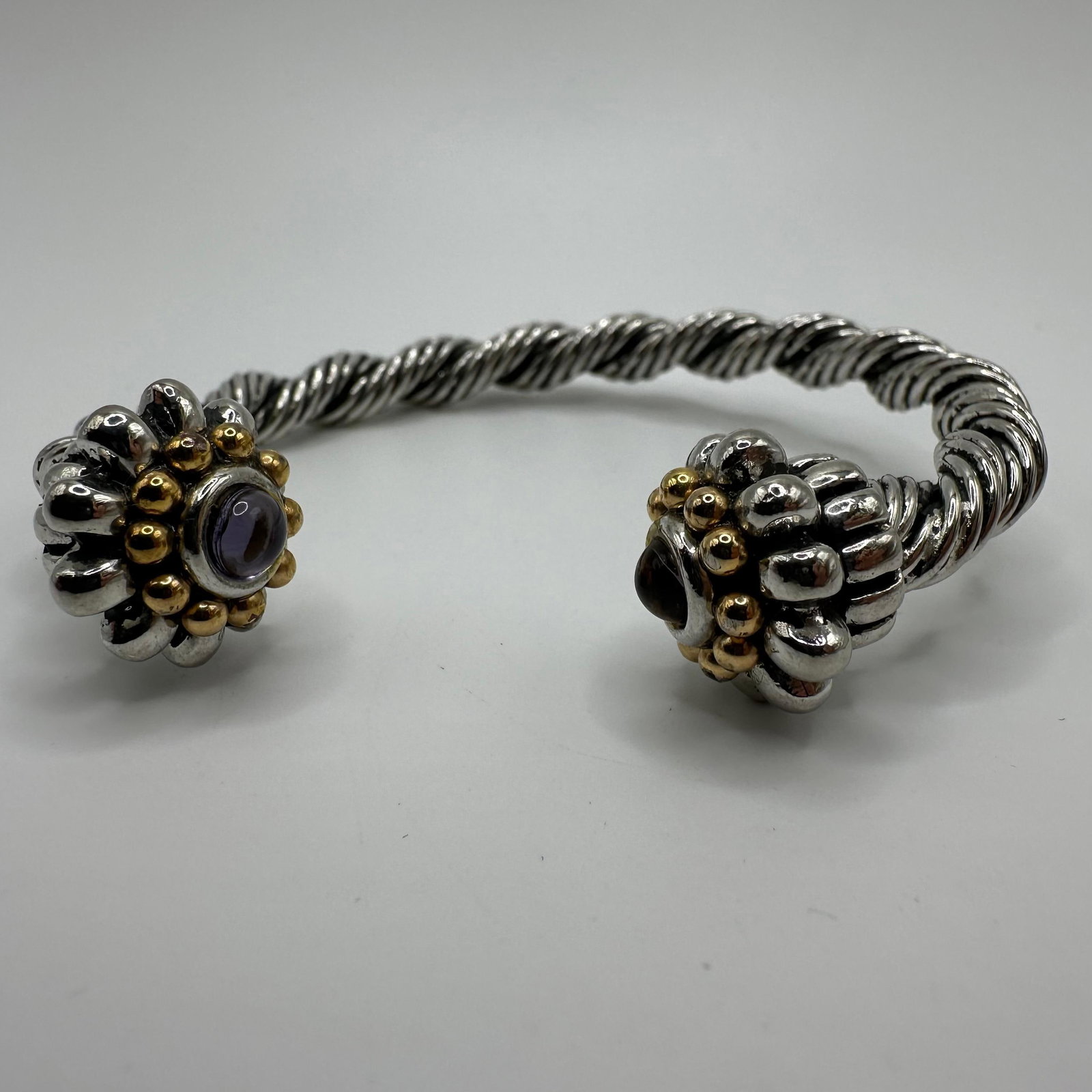 Twisted Cable Design Silver and Gold Tone Purple Glass Accent Cuff Bracelet: No hallmarks. Silver and gold-toned base metal with purple glass accents. This item is in good pre-owned, previously displayed condition with light wear and surface markings. Please reference all