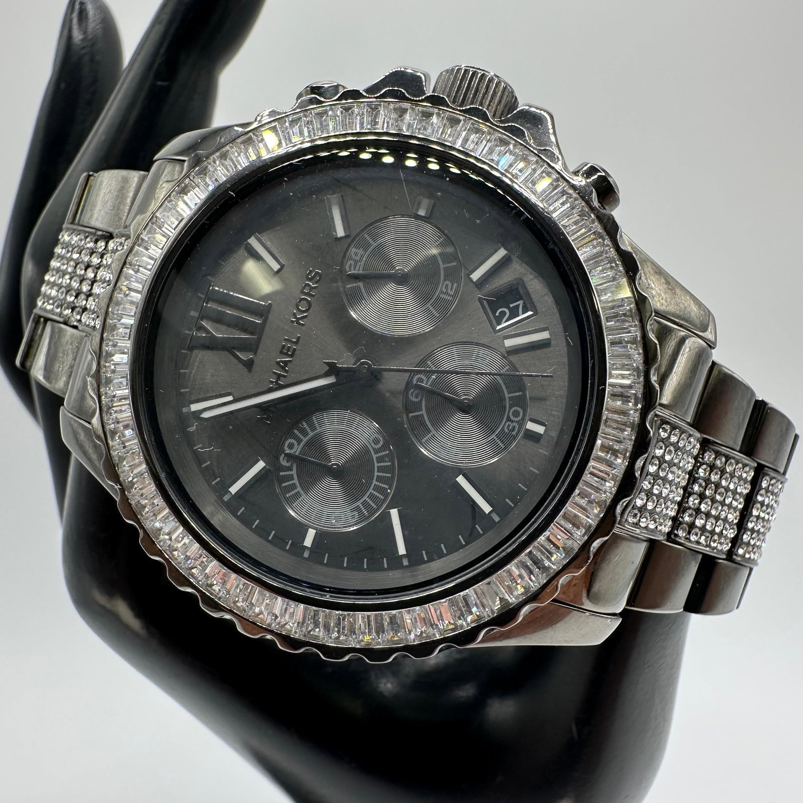 Michael Kors Gunmetal Chronograph Watch Crystal Bezel Date MK5829: Michael Kors wristwatch in gunmetal stainless steel with a crystal-set bezel and matching crystal-accented bracelet links. Black dial with Roman numeral markers, chronograph subdials, and date display