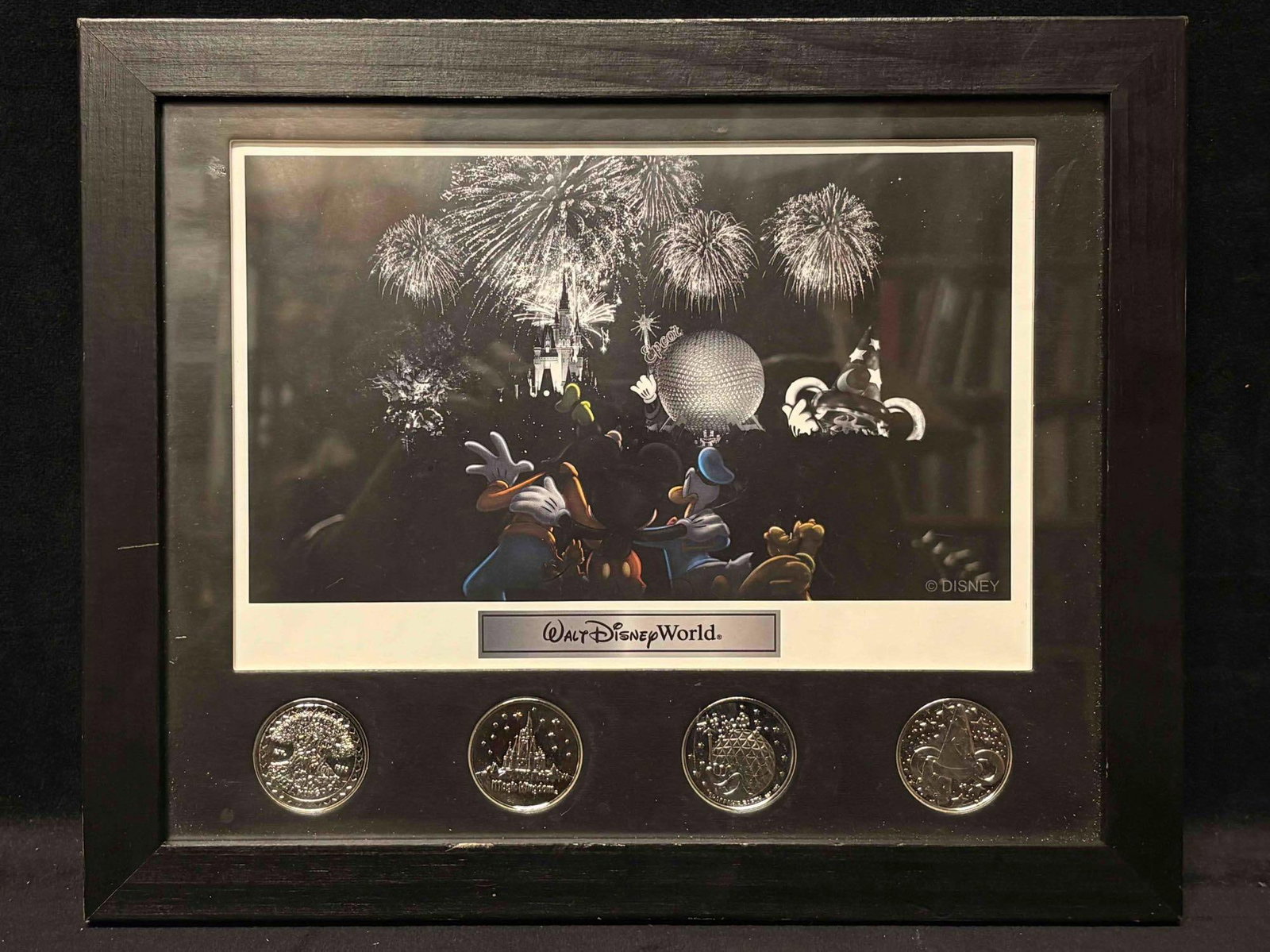 Walt Disney Worlds Framed Four Park Coin Set: This set includes a black and white framed print of Disney characters watching fireworks, with four (4) silver-toned coins. Each coin represents a different Walt Disney World theme park icon; Animal K