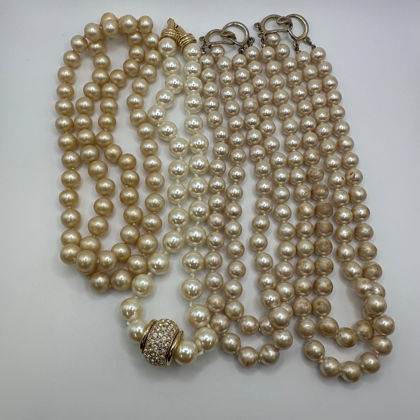 Group of Vintage Faux Pearl Necklaces One with Rhinestone Clasp Set of Four: Group of vintage faux pearl jewelry, including single and multi-strand necklaces. Includes one necklace with a rhinestone-set style clasp. Pearls vary slightly in size and tone with visible wear and d