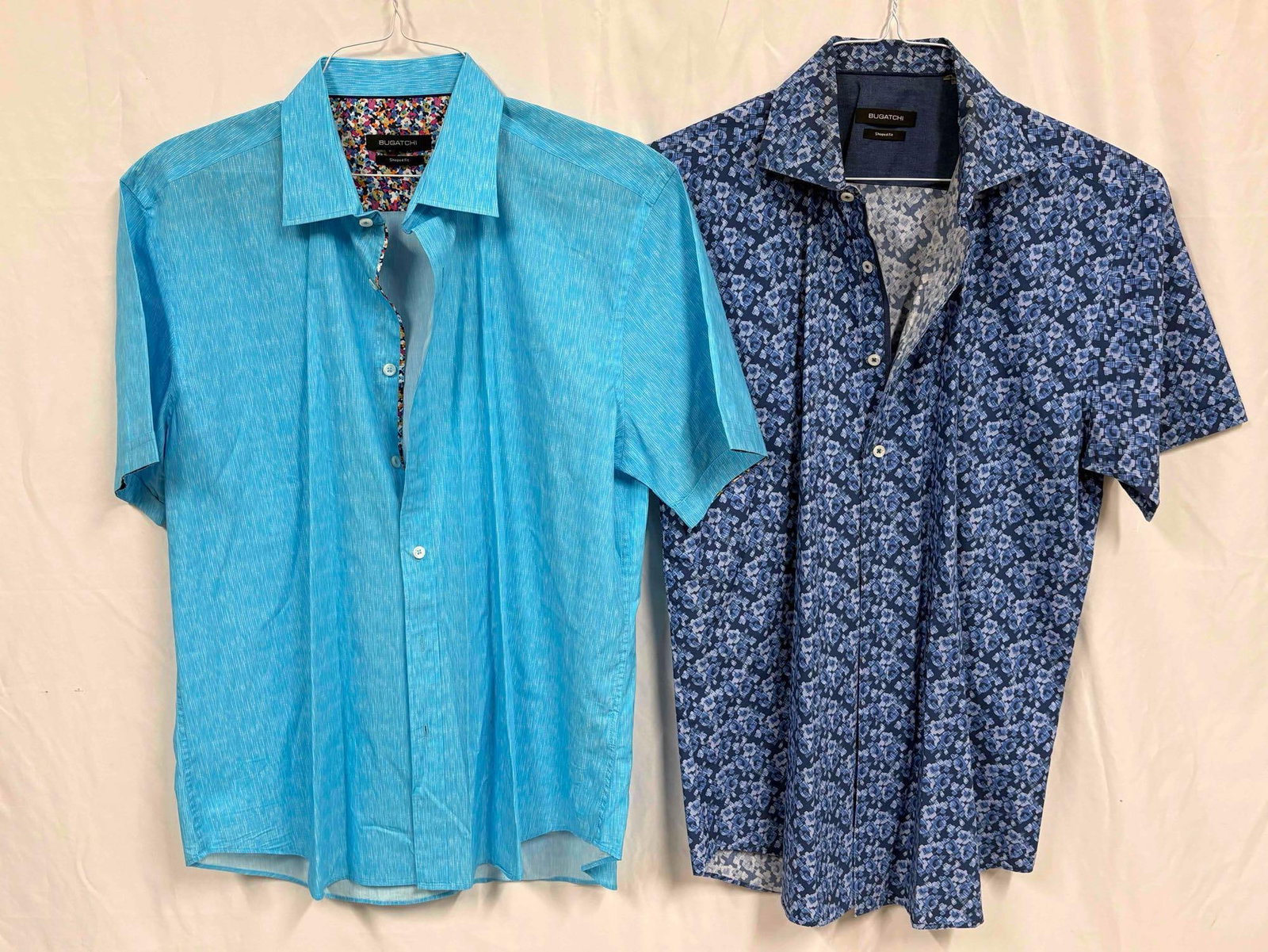 2PC Bugatchi Blue Shaped Fit Men's Button-Up Shirt Bundle: This lot contains a set of men's short sleeve dress shirts by Bugatchi, a luxury menswear brand founded in the 80s. Both shirts are a size Large, standing in like-new conditions without tags. Plea