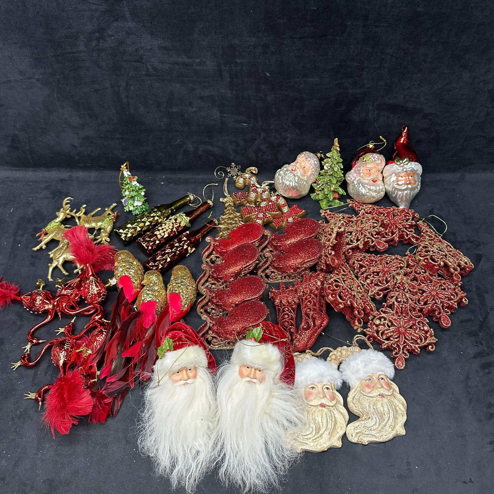 Large Mixed Christmas Ornament Lot Santa Reindeer Birds Glass And Decorative Holiday Pieces: Large group of assorted Christmas ornaments and holiday decorations, including Santa head ornaments, reindeer figures, birds with feather tails, sleigh forms, stocking shapes, and ornate filigree snow