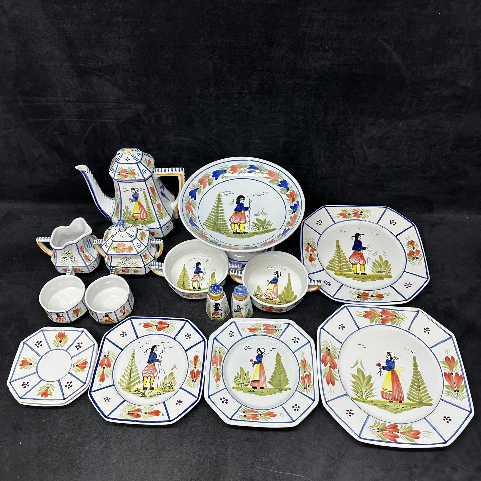 HB Quimper French Faience Hand-Painted Tea and Tableware Set with Comport: Group of hand-painted French faience ceramics marked HB Quimper France, featuring traditional Breton figures and floral motifs. The lot includes a teapot, covered sugar, creamer, cups, handled bowls, 