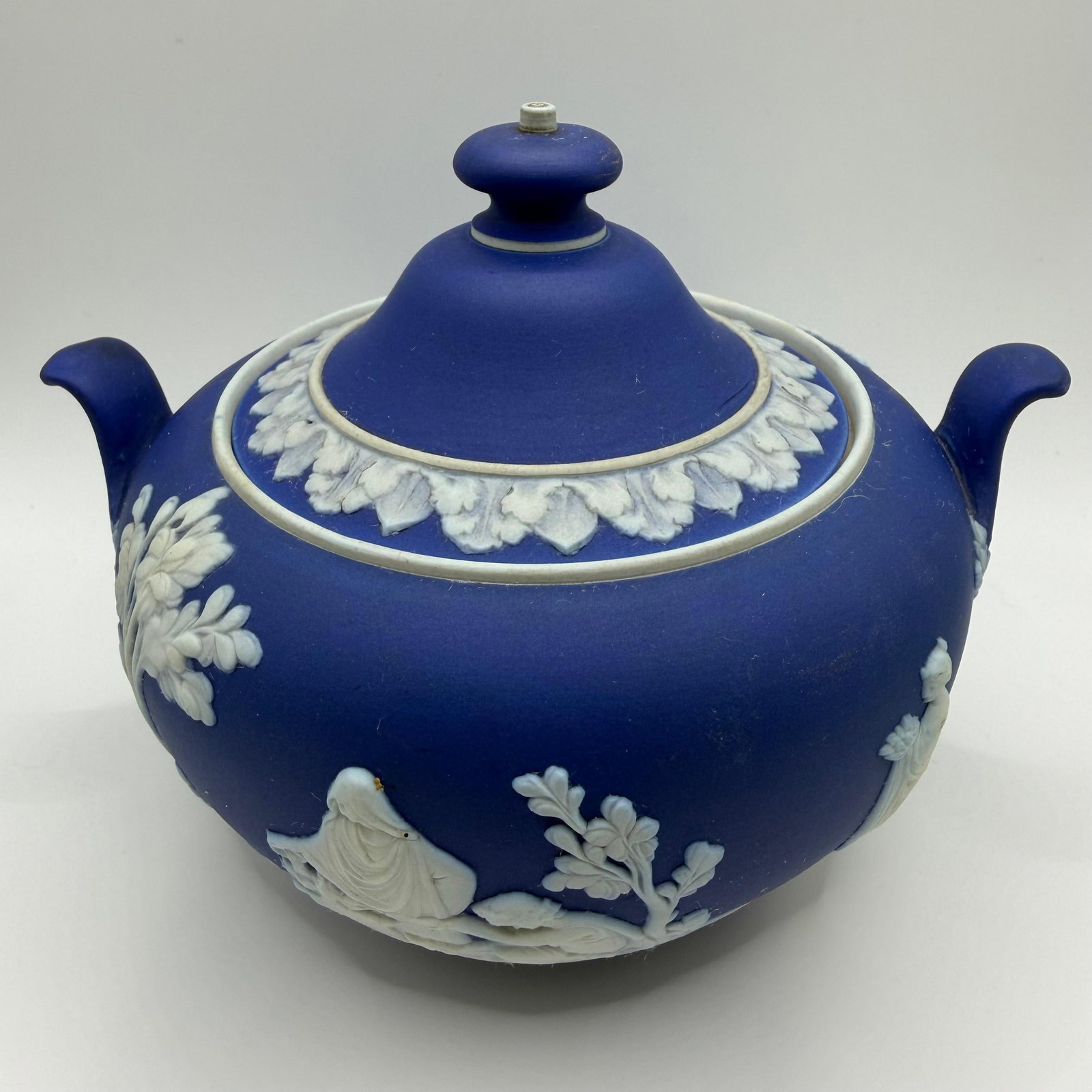 Wedgwood Blue Jasperware Covered Sugar Bowl England: Classic Wedgwood blue jasperware covered sugar bowl featuring white applied neoclassical relief figures, floral garlands, and decorative borders. Includes a matching fitted lid with dual handles. Base