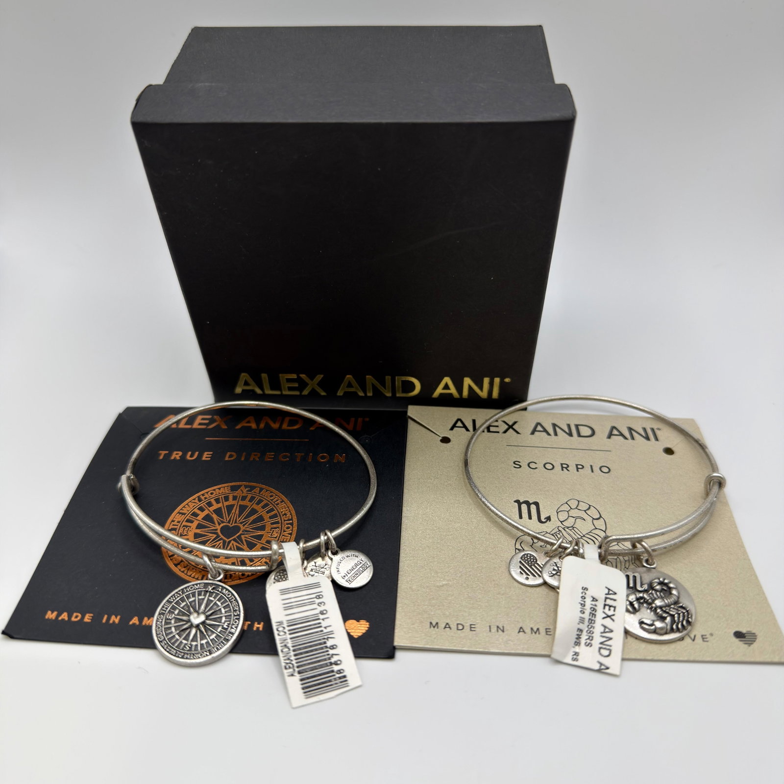 Alex and Ani Charm Bangle Bracelets True Direction and Scorpio Set: Lot of two Alex and Ani expandable charm bangles with original packaging and presentation box. Includes the True Direction bracelet featuring a compass charm and the Scorpio zodiac bracelet featuring 