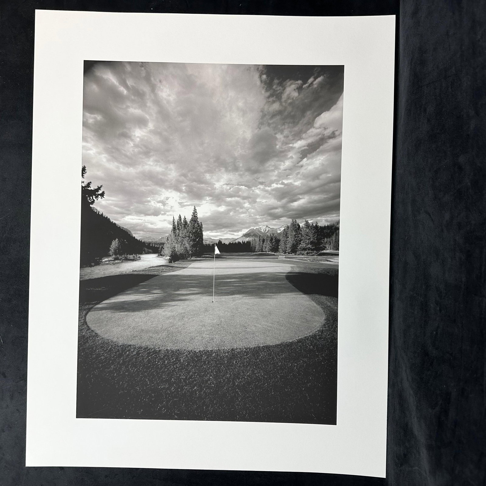 Black and White Fine Art Photograph Print Golf Course Landscape with Mountain View: Black and white fine art photograph, ink jet print featuring a golf course green framed by a dramatic sky, distant mountains, and evergreen trees. Unmarked on reverse. This item is in pre-owned, previ